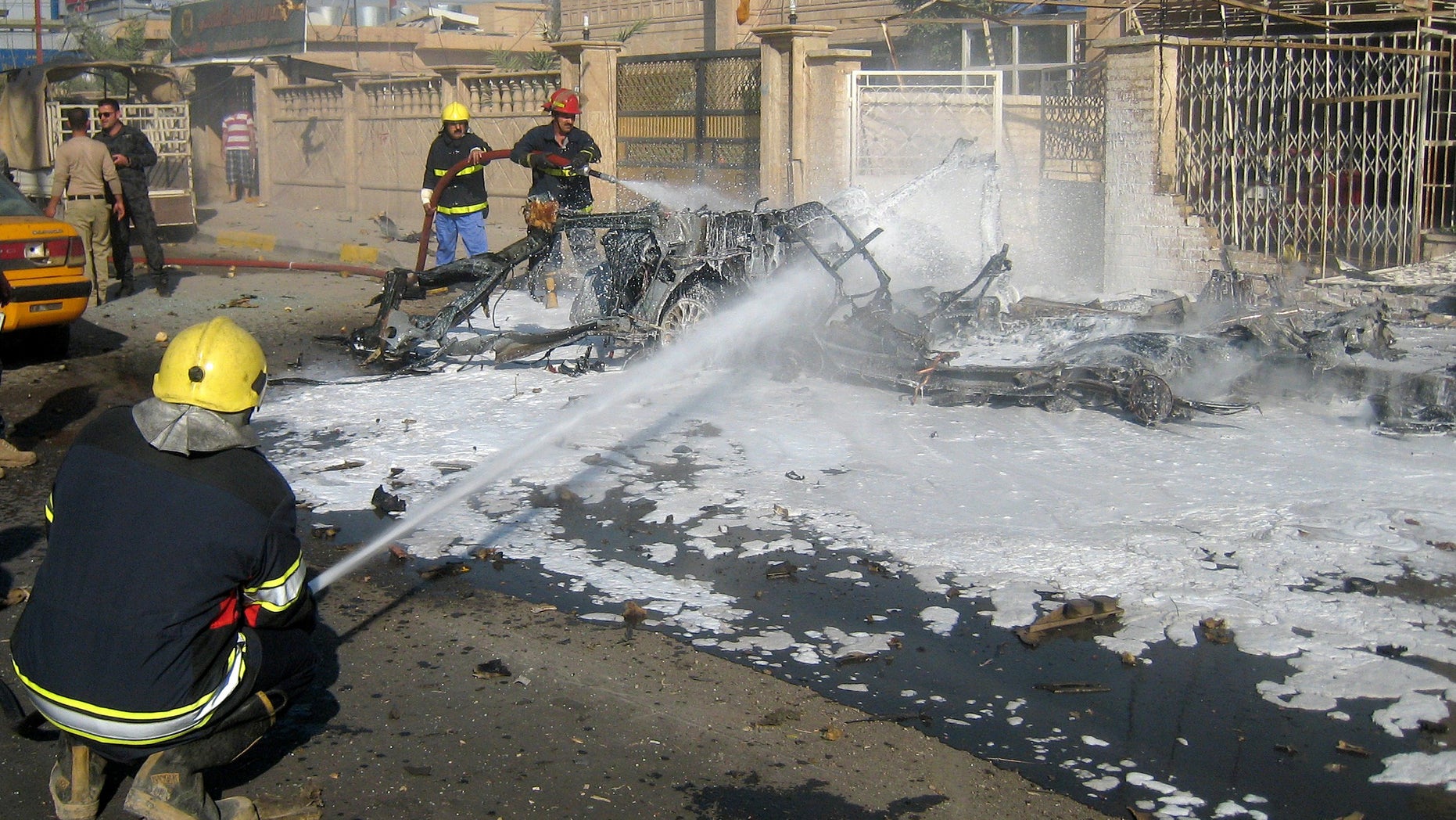 Iraqi firefighters hose down a burned car after a car bomb attack in Kirkuk, 180 miles (290 kilometers) north of Baghdad, Iraq, Tuesday, Nov. 5, 2013. A parked car bomb went off in front of Iraqi Islamic Bank in Kirkuk, home to a mix of Arabs, Kurds and Turkomen, each of the ethnic groups has competing claims to the oil-rich area, the Kurds want to incorporate it into their self-ruled region in Iraq's north, but Arabs and Turkomen are opposed. (AP Photo/Emad Matti)