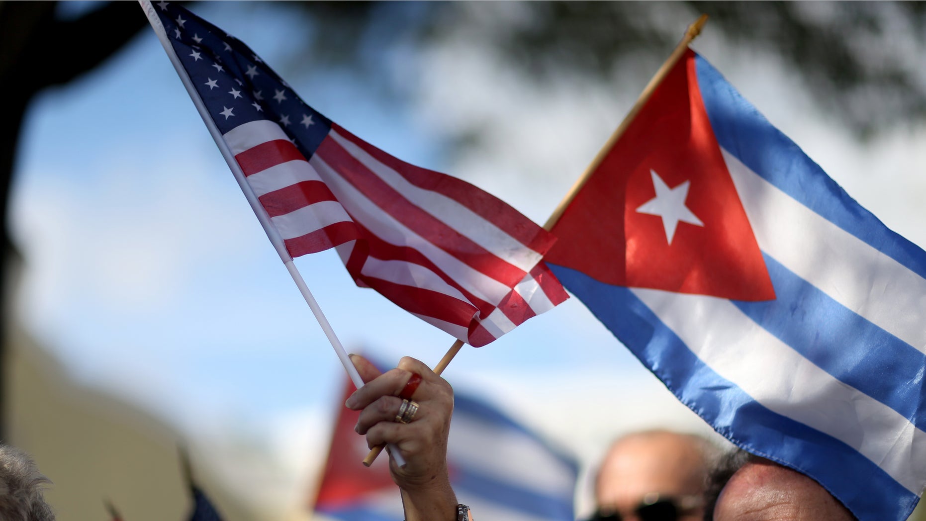 MIAMI, FL - DECEMBER 20: A protester holds an American flag and a Cuban one as she joins with others opposed to U.S. President Barack Obama's announcement earlier in the week of a change to the United States Cuba policy stand together at Jose Marti park on December 20, 2014 in Miami, Florida. President Obama announced a move toward normalizing the relationship with Cuba after a swap of prisoners took place. (Photo by Joe Raedle/Getty Images)