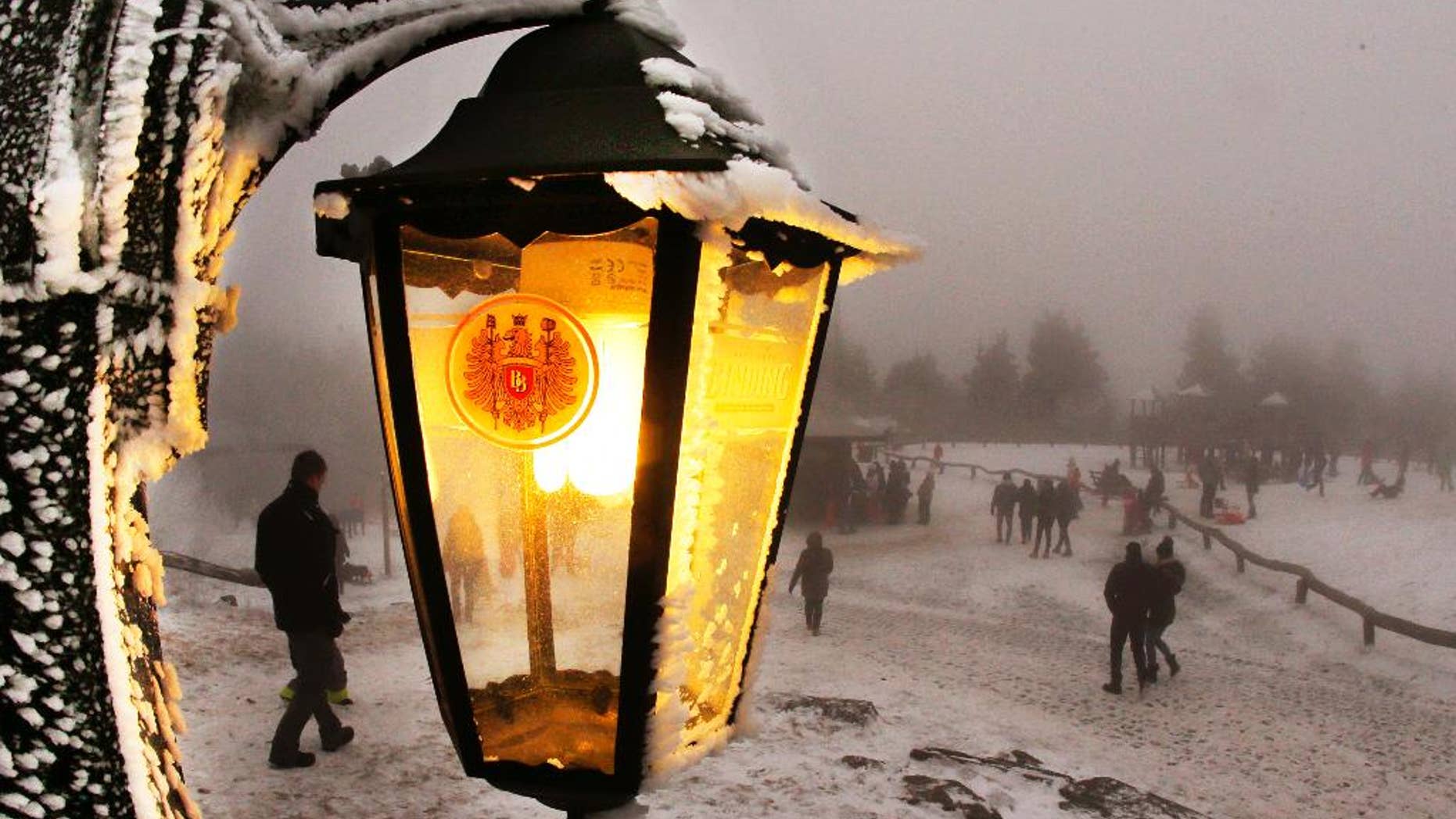 A lamp of a restaurant shines as trippers walk by in thick fog on top of the 880 m high Feldberg mountain near Frankfurt, Germany, Monday, Jan. 2, 2017. (AP Photo/Michael Probst)