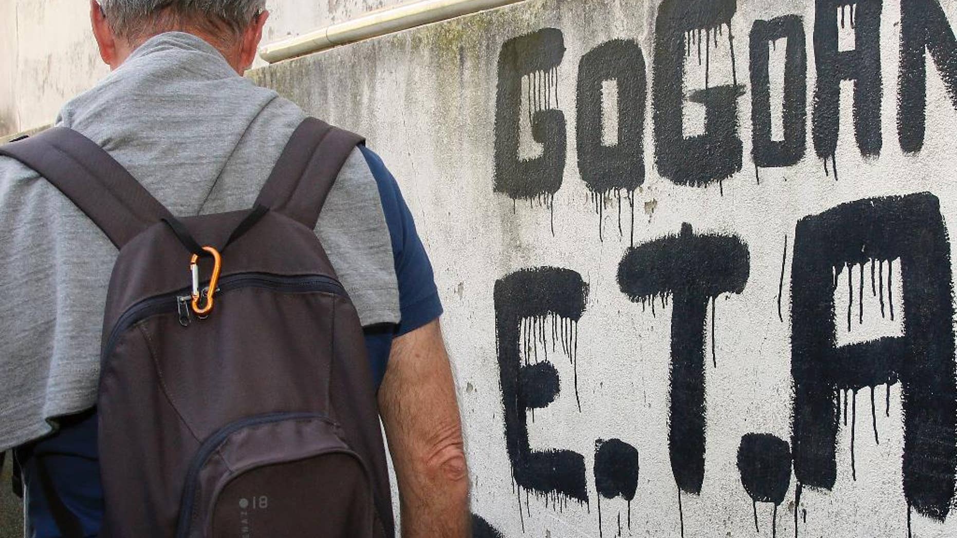 A man walks past graffiti reading "ETA , Basque country and Freedom", in Sare, southwestern France, Friday, April 7, 2017. The armed Basque separatist group ETA, inactive for more than five years, is to hand over its arms Saturday, a finishing touch to a 43-year violent campaign that claimed 829 lives, mostly in Spain. (AP Photo/Bob Edme)