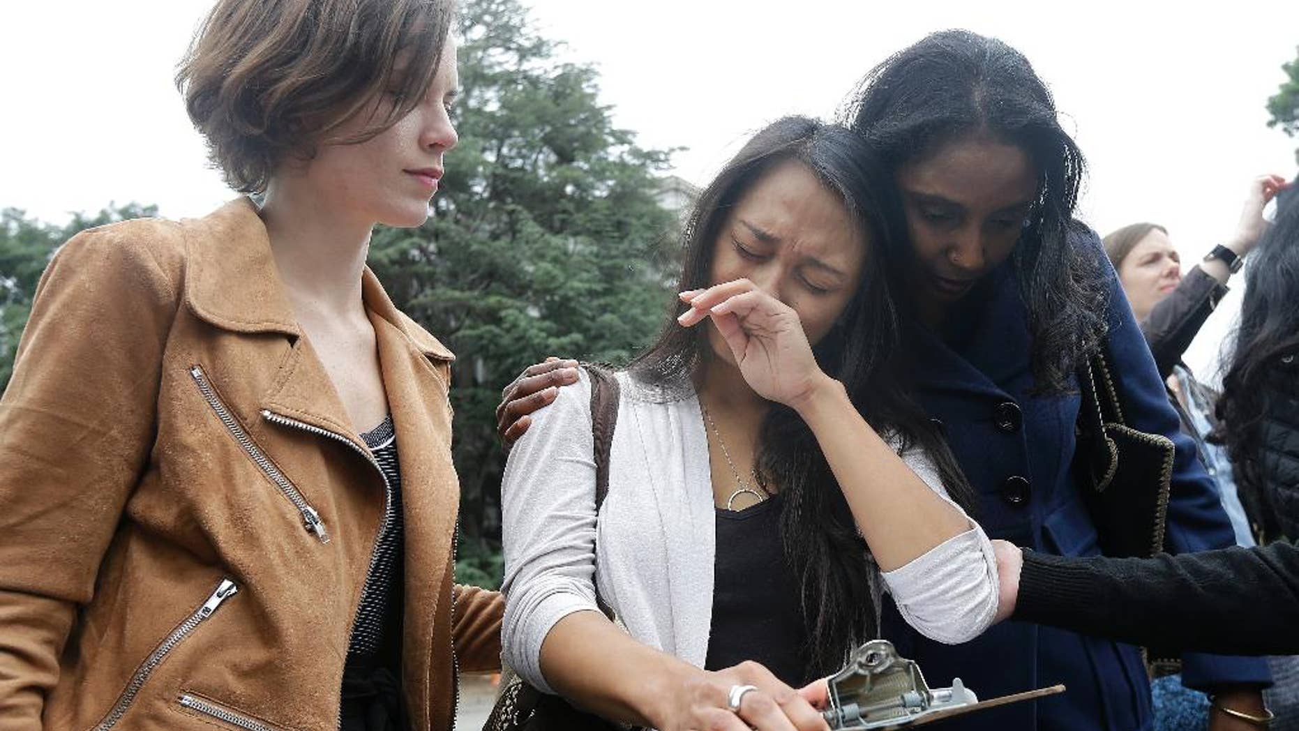 University of California graduate student Kathleen Gutierrez, center, is comforted by graduate student Erin Bennett, left, and Tyann Sorrell before all spoke at a news conference outside of Dwinelle Hall on the campus in Berkeley, Calif., Monday, April 11, 2016. Bennett and Gutierrez have filed a complaint regarding alleged sexual harassment by a University of California Berkeley professor. Sorrell has also made complaints against the same individual for sexual harassment. (AP Photo/Jeff Chiu)