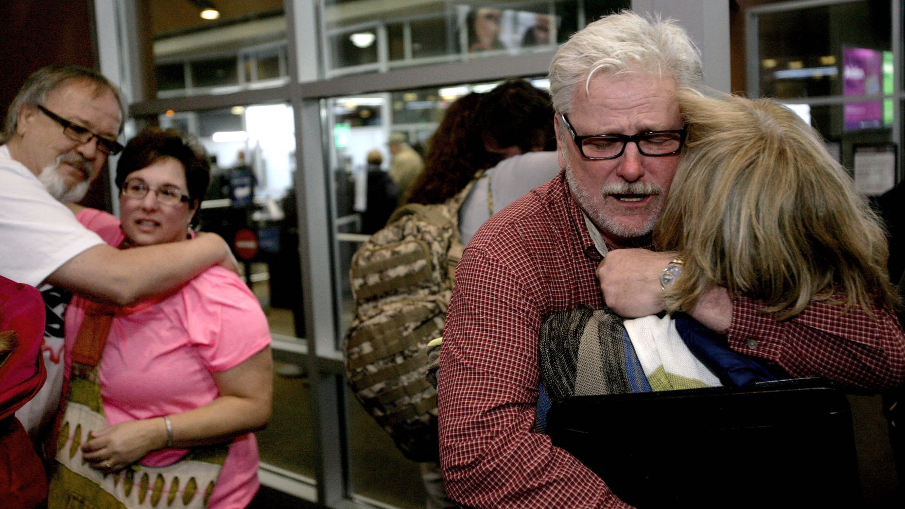 Freed aid workers Arlynn Hefta, right, and Kermit Paulson, left, embrace their wives at Hector International Airport, Tuesday, March 3, 2015 in Fargo, N.D.