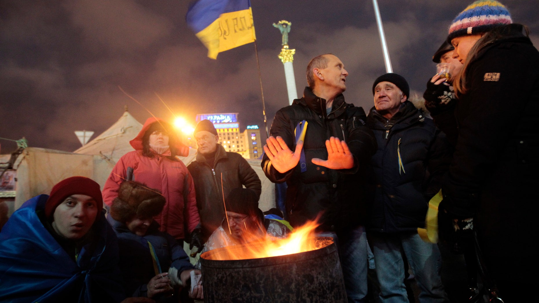 Protesters warm themselves around a fire in Independent Square in Kiev, Ukraine, Saturday, Dec. 7, 2013. As thousands of anti-government protesters kept their vigil in Ukraine's capital Saturday, officials sought to reduce their anger with assurances that Russian and Ukrainian presidents didn’t discuss Ukraine joining a Russian-led customs union at a meeting this week. (AP Photo/Sergei Chuzavkov)