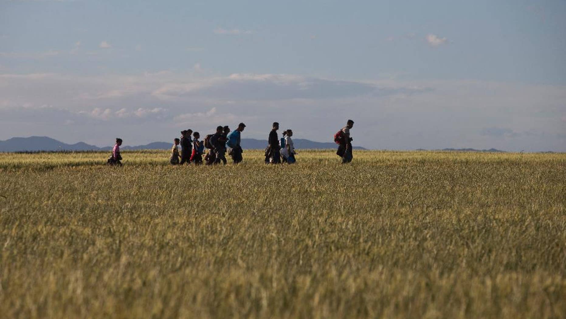 Migrants and refugees walk among fields on their way to Idomeni camp, after trying to cross the Greek-Macedonian border, Saturday, May 14, 2016. Thousands of stranded refugees and migrants are camped at the makeshift refugee camp of the northern Greek border point of Idomeni. (AP Photo/Petros Giannakouris)