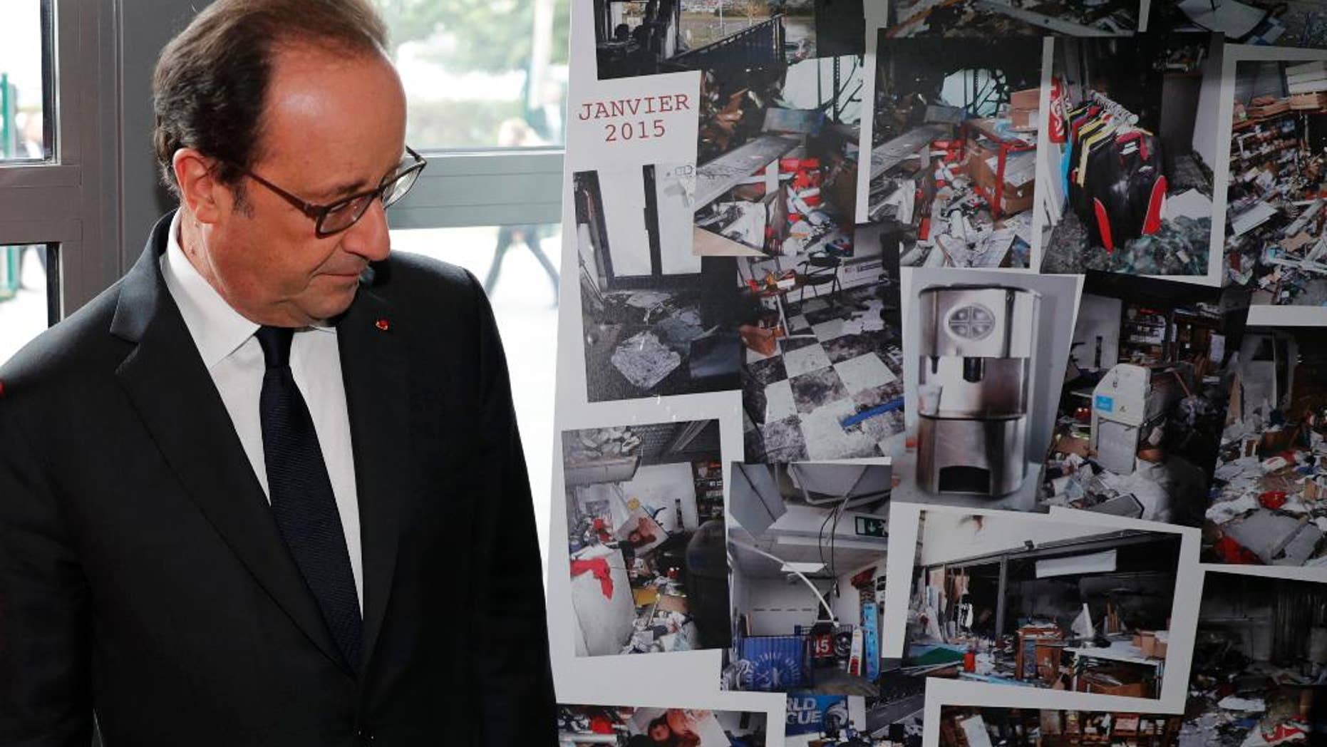 French President Francois Hollande walks past photographs of the devastated printing plant after the attack, as the plant reopens Thursday.