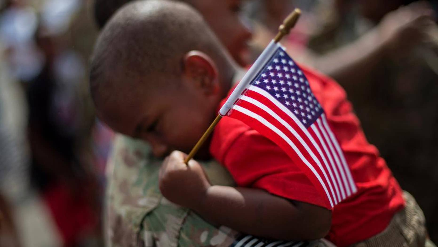 Tyson Hicks, 2, holds an American flag while embraced by his father Sgt. 1st Class Gabriel Hicks upon returning from a deployment to Afghanistan with the Georgia National Guard's 48th Infantry Brigade Combat Team, Tuesday, Sept. 16, 2014, in Macon, Ga. Two hundred Guardsmen returned home Tuesday from a nine-month deployment where they provided security and facilitated the transfers of U.S. military installations to their Afghan counterparts. (AP Photo/David Goldman)