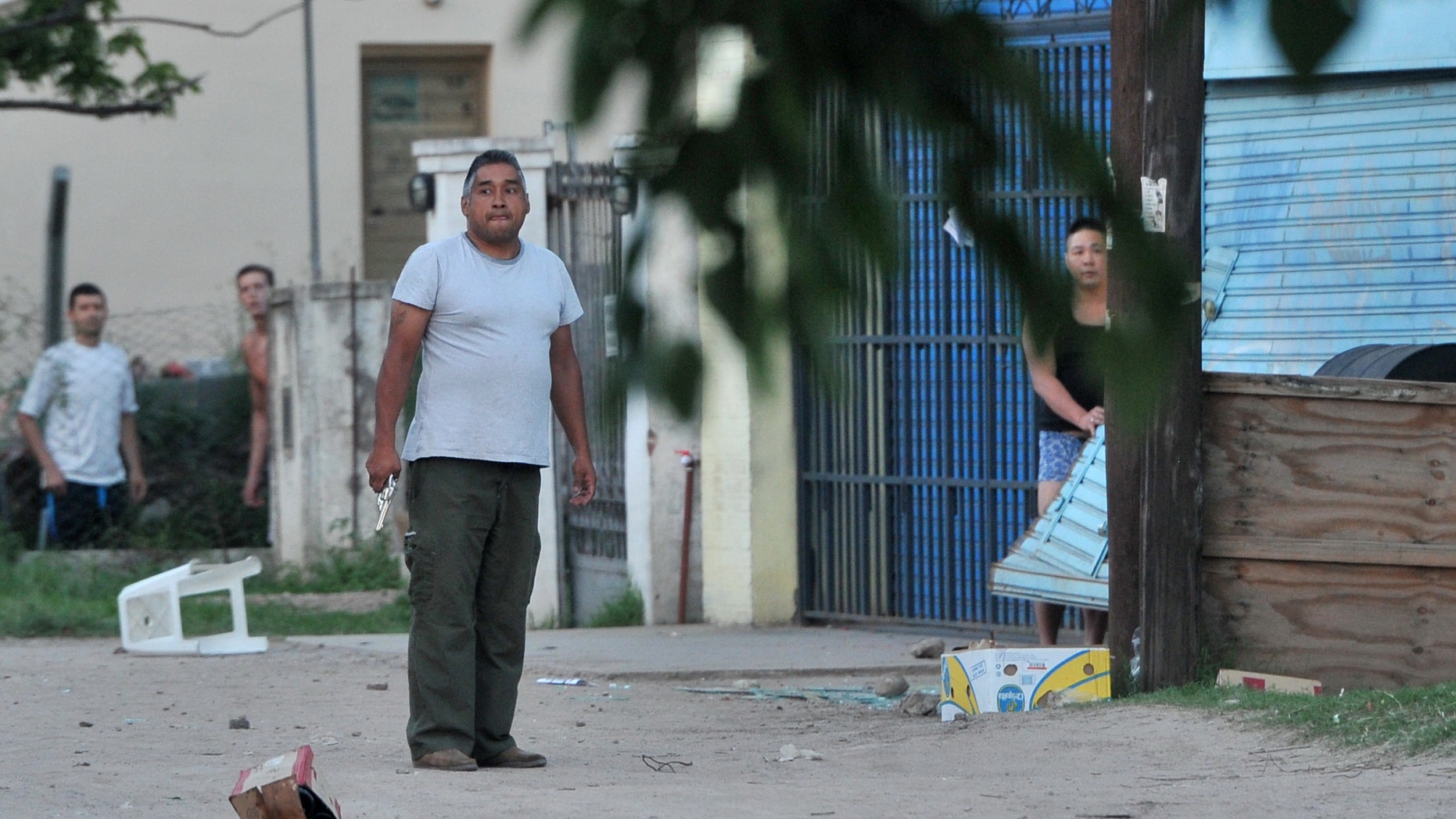 An armed shopkeeper stands outside his business after his shop was looted in Cordoba, Argentina, Tuesday, Dec. 3, 2013. Looting and robberies continue in Cordoba, Argentina’s second-largest city, where police striking for higher pay have left citizens at the mercy of the mob. Many people have armed themselves to defend their neighborhoods. (AP Photo/La Voz del Interior,Antonio Carrizo)