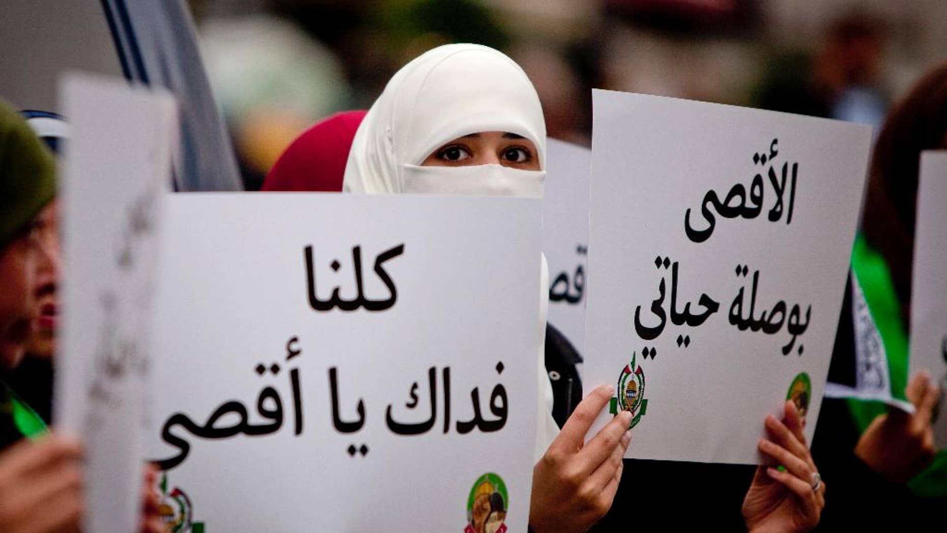 Palestinian supporters of the Islamist movement Hamas, hold a placards with the slogan written in Arabic, "we are all your defenders Al-Aqsa,", and "Al-Aqsa is the compass for my life" during a protest against recent Israeli restrictions at the Al-Aqsa Mosque, in the West Bank City of Ramallah, Friday, Oct. 17, 2014. (AP Photo/Majdi Mohammed)
