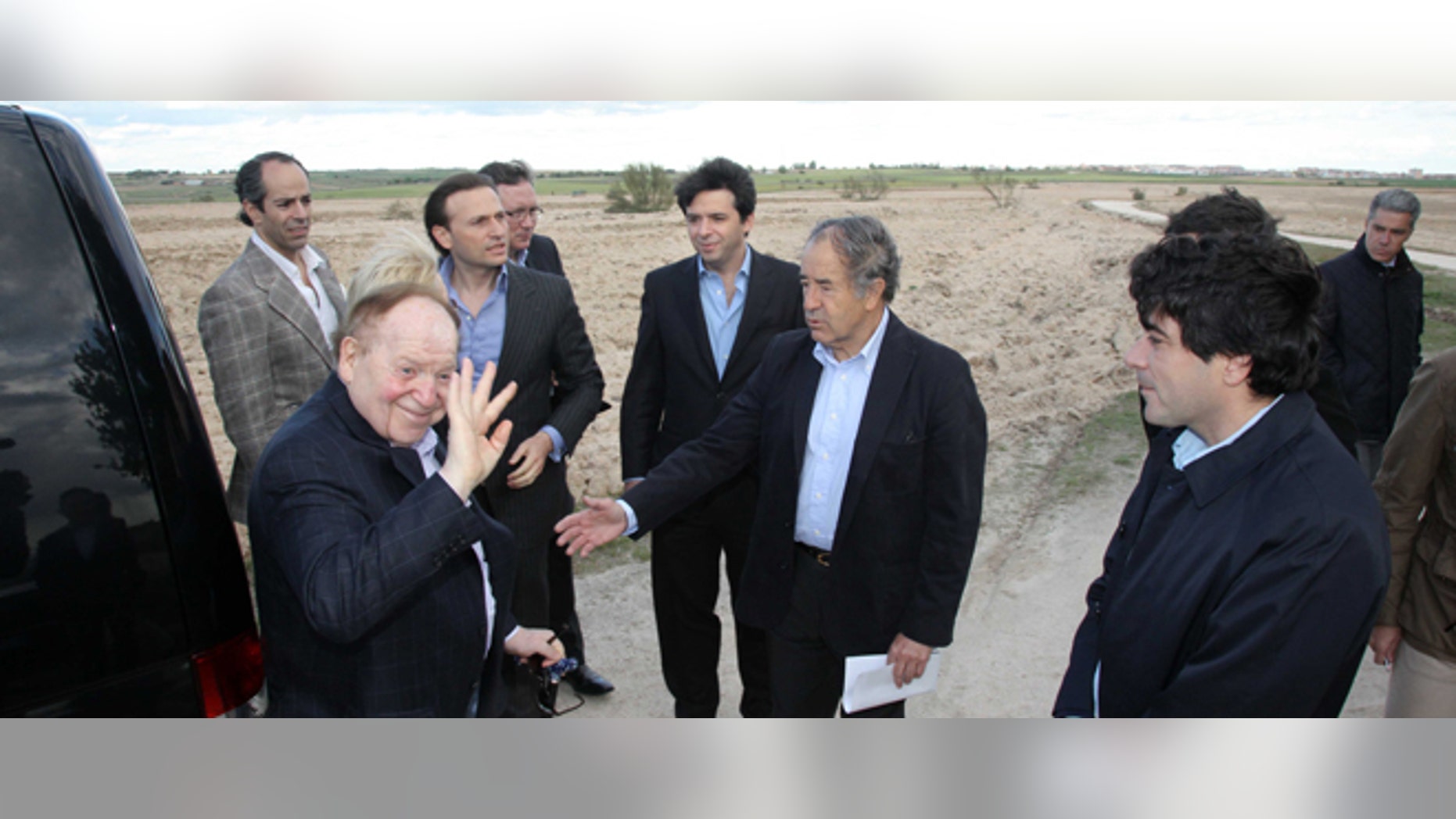In this photo released by the Madrid Regional Government on May 6, 2012, CEO of Las Vegas Sands Corp. Sheldon Adelson, left in foreground, waves while visiting Alcorcon, which was one of the possible sites for the EuroVegas project on the outskirts of Madrid, with others unidentified. (AP Photo/Comunidad de Madrid)