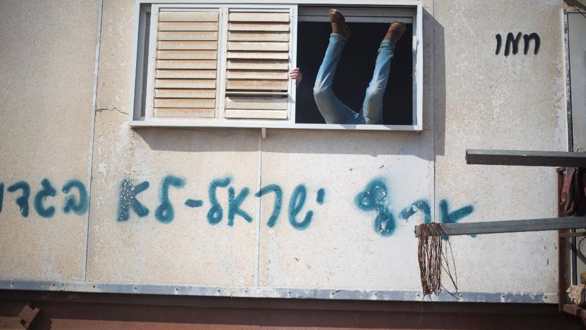A settler jumps into a trailer in Amona outpost in the West Bank, Wednesday, Feb. 1, 2017. Israeli forces have begun evacuating a controversial settlement Amona, which is the largest of about 100 unauthorized outposts erected in the West Bank without permission but generally tolerated by the Israeli government. The writing reads: "Eretz Israel we did not betray ". (AP Photo/Ariel Schalit)