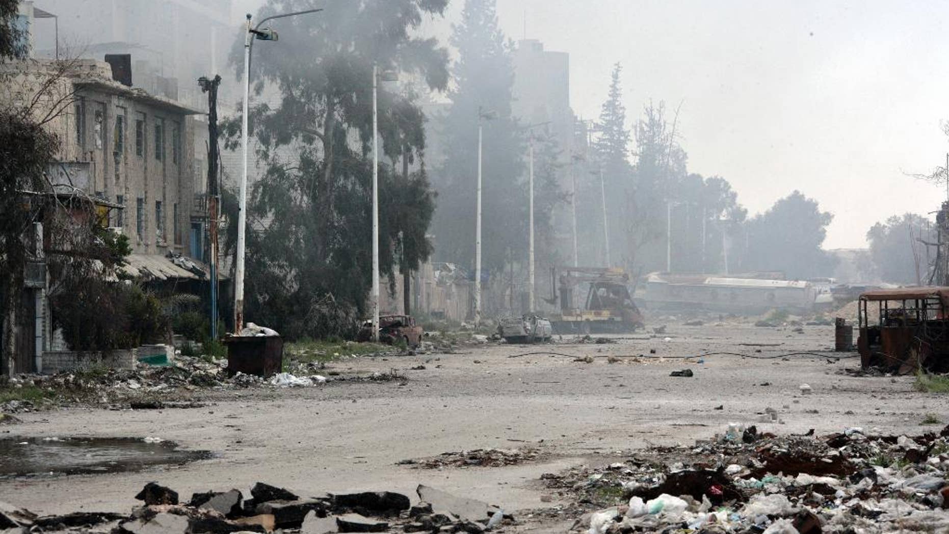In this photo released by the Syrian official news agency SANA, damaged and blocked street where clashes erupted between the Syrian government forces and rebels, near the Abbassiyin square, east Damascus, Syria, Monday March 20, 2017. Syrian government forces on Monday regained control of parts of Damascus that were attacked and captured by rebels and militants the previous day, with the two-day fighting leaving dozens dead on both sides, the military and an activist group said. (SANA via AP)