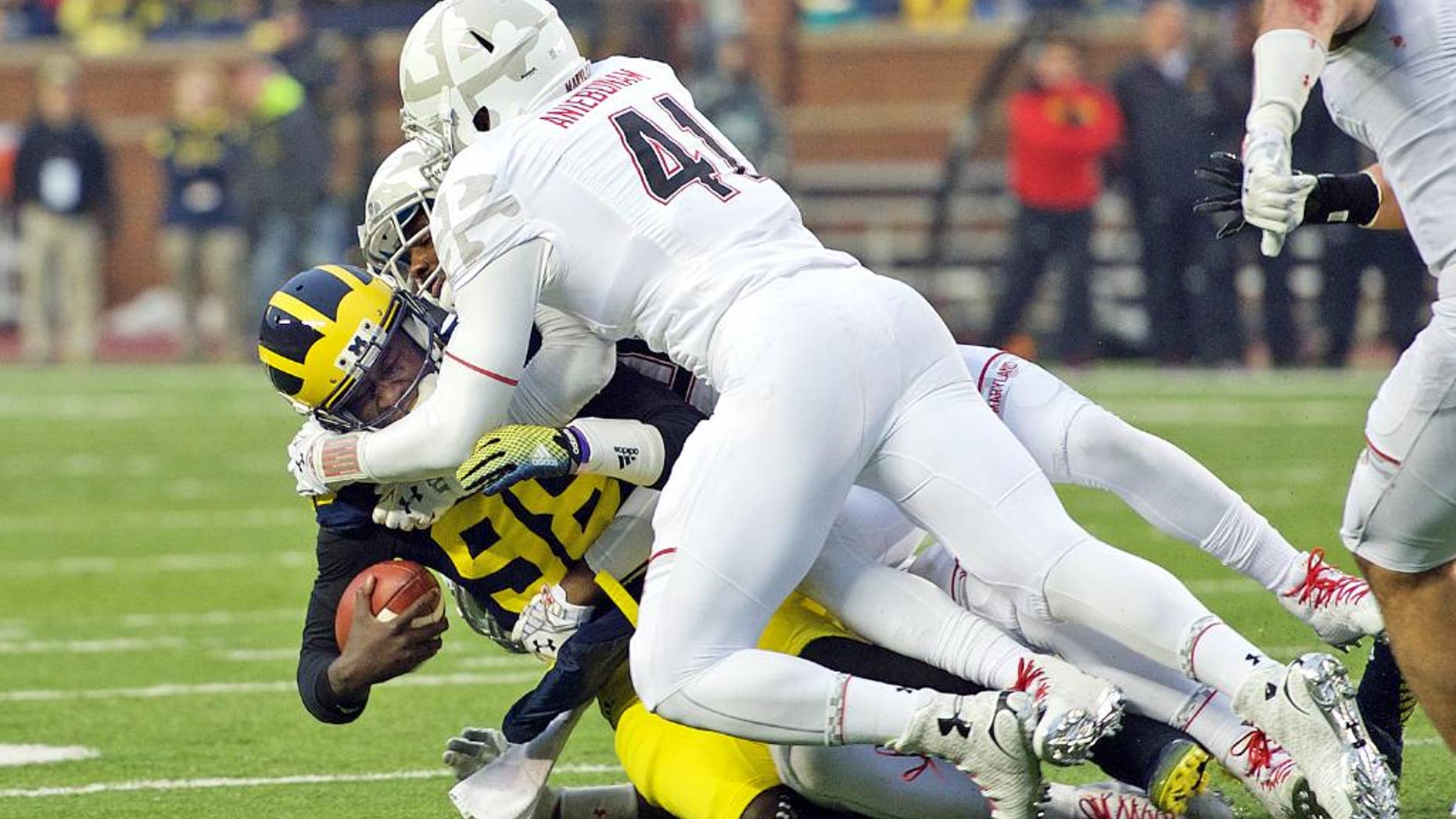Michigan quarterback Devin Gardner, bottom left, gets sacked by Maryland linebackers Yannick Ngakoue, back, and Jesse Aniebonam (41), in the second quarter of an NCAA college football game in Ann Arbor, Mich., Saturday, Nov. 22, 2014. Maryland won 23-16. (AP Photo/Tony Ding)