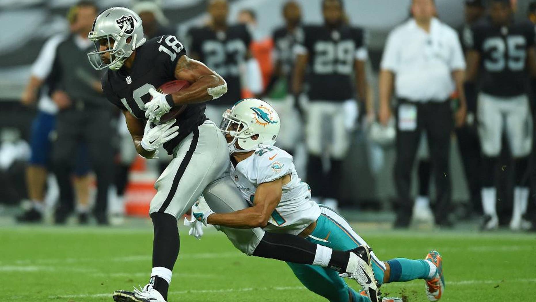 Oakland Raiders' Andre Holmes is tackled by Miami Dolphins' Brent Grimes during the NFL football game at Wembley Stadium in London, Sunday, Sept. 28, 2014. (AP Photo/Tim Ireland)