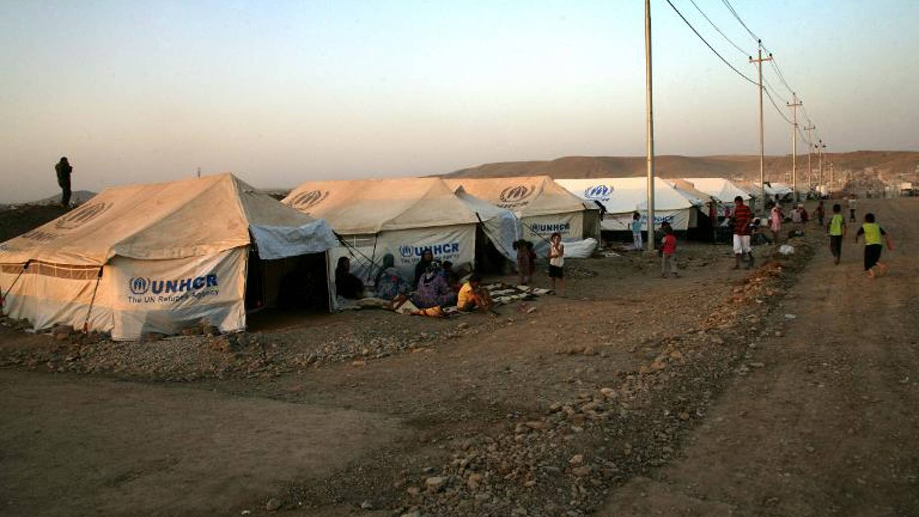 A file picture taken on August 27, 2013, shows Kurd refugees from Syria sitting outside tents provided by the UN High Commission for Refugees (UNHCR) at the Quru Gusik refugee camp in northern Iraq
