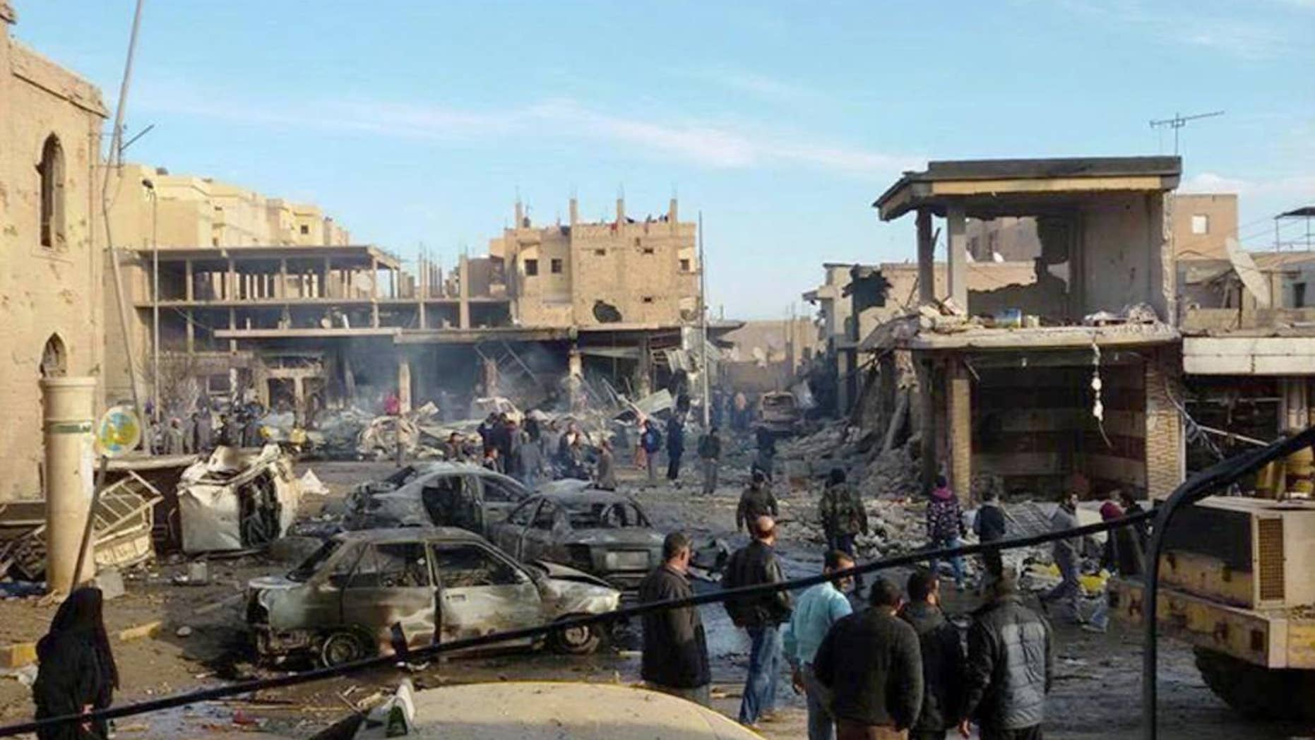 This photo provided on Tuesday, Nov. 25, 2014, by an anti-Islamic State group and anti-Bashar Assad activist group Raqqa Is Being Slaughtered Silently, which has been authenticated based on its contents and other AP reporting, showa burned cars and damaged buildings on a street after Syrian government forces airstrikes struck a popular market near a museum and an industrial neighborhood in Raqqa city, north Syria. The death toll from a series of Syrian government airstrikes on the Islamic State group's stronghold in northeastern Syria has risen to at least 95, making it one of the deadliest attacks on the city of Raqqa in the past three years. (AP Photo/Raqqa Is Being Slaughtered Silently)