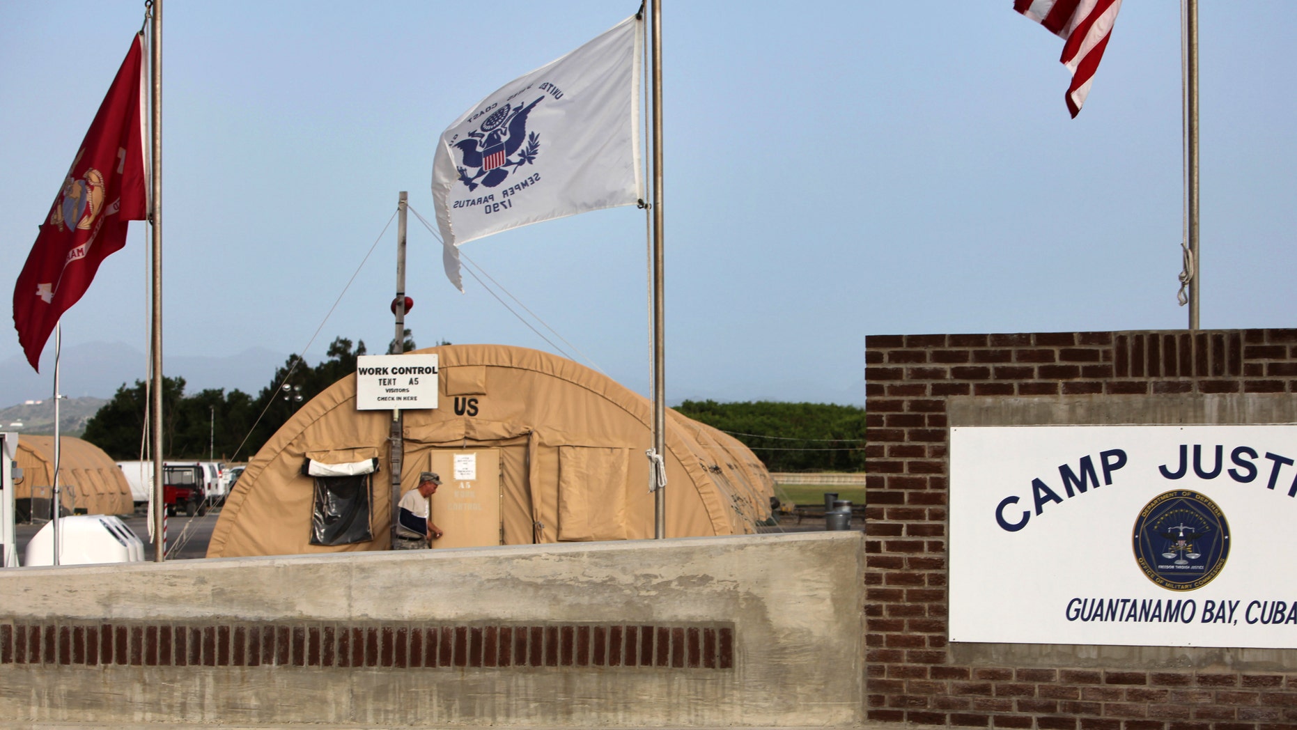 FILE - In this July 16, 2009 file photo, reviewed by the U.S. military, flags hang above the sign marking the Camp Justice compound, the site of the U.S. war crimes tribunal, at Guantanamo Bay U.S. Naval Base, Cuba. President Barack Obama's speech national security speech Thursday is expected to reaffirm his national security priorities _ from homegrown terrorists to killer drones to the enemy combatants held at the military-run detention center at Guantanamo Bay, Cuba _ but make no new sweeping policy announcements. (AP Photo/Brennan Linsley, File)