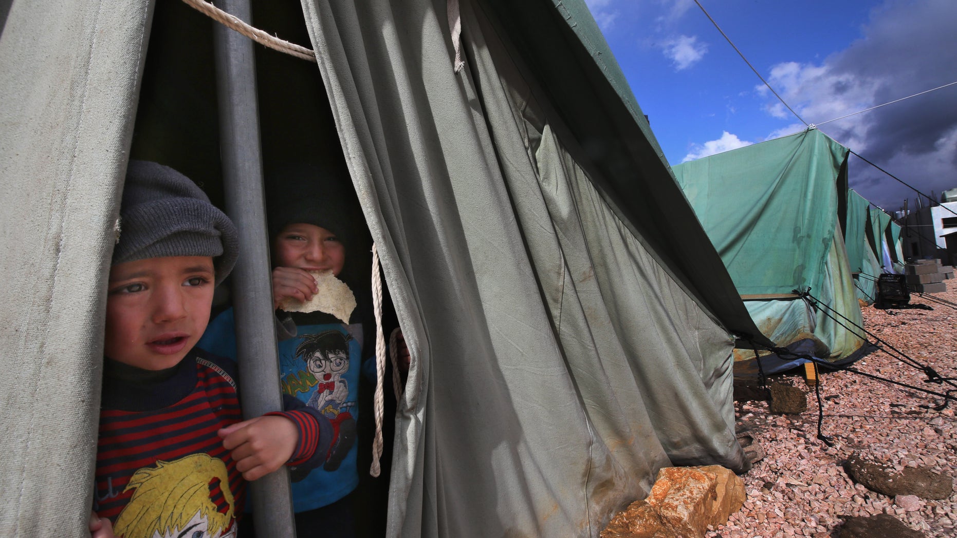 Syrian refugee boys look outside their tent, at a temporary refugee camp in the eastern Lebanese town of Marj near the border with Syria, Lebanon, Monday, Jan. 7, 2013. Syrian refugees worked on reinforcing their tents after they were flooded and some blown away by torrential rains and high winds. A heavy rainstorm coupled by snow on medium altitudes and high winds is hitting Lebanon causing material damage, flooding and trapping people in their cars. Particularly hard hit are thousands of Syrian refugees who fled to Lebanon, some of whom are staying in tents near the border with Syria. (AP Photo/Hussein Malla)