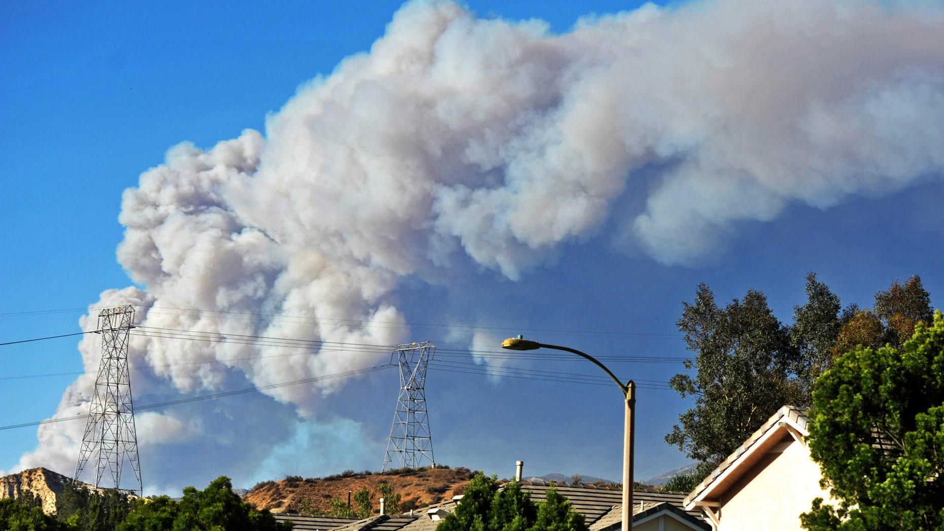 Smoke from the Powerhouse Fire is visible from the Saugus neighborhood of Santa Clarita, Calif., Thursday, May 30, 2013. The fire in the Angeles National Forest surged to 1,000 acres after burning for about four hours, the U.S. Forest Service said, sending out big clouds of black smoke amid temperatures in the high 80s and winds gusting at more than 20 mph. (AP Photo/Santa Clarita Valley Signal, Jonathan Pobre) MANDATORY CREDIT