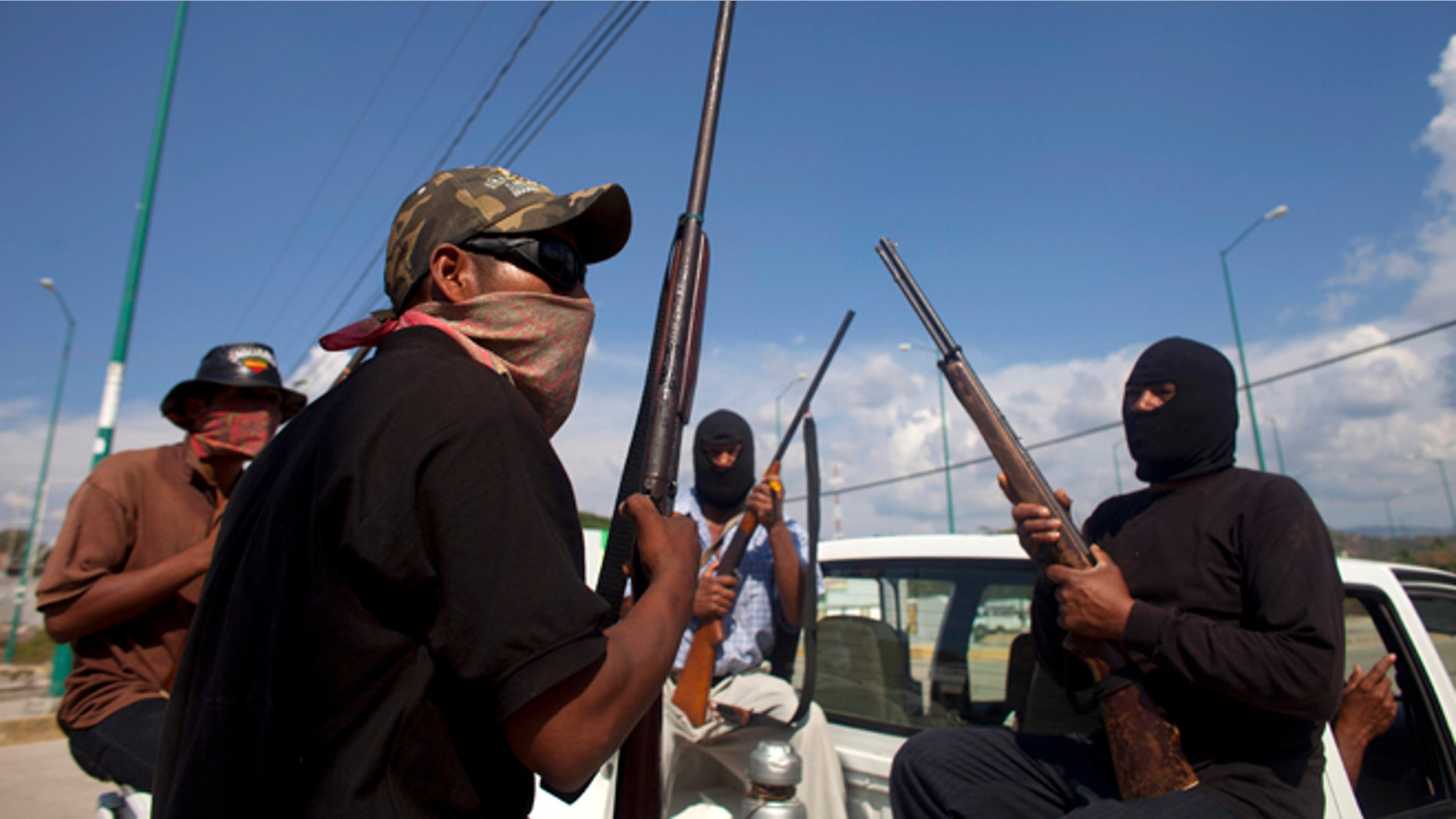 Jan. 18, 2013: In this photo, masked and armed men sit in the back of a pick-up truck at the entrance to the town of Ayutla, Mexico. Hundreds of men in the southern Mexico state of Guerrero have taken up arms to defend their villages against drug gangs, a vigilante movement born of frustration at extortion, killings and kidnappings in a region wracked by violence.