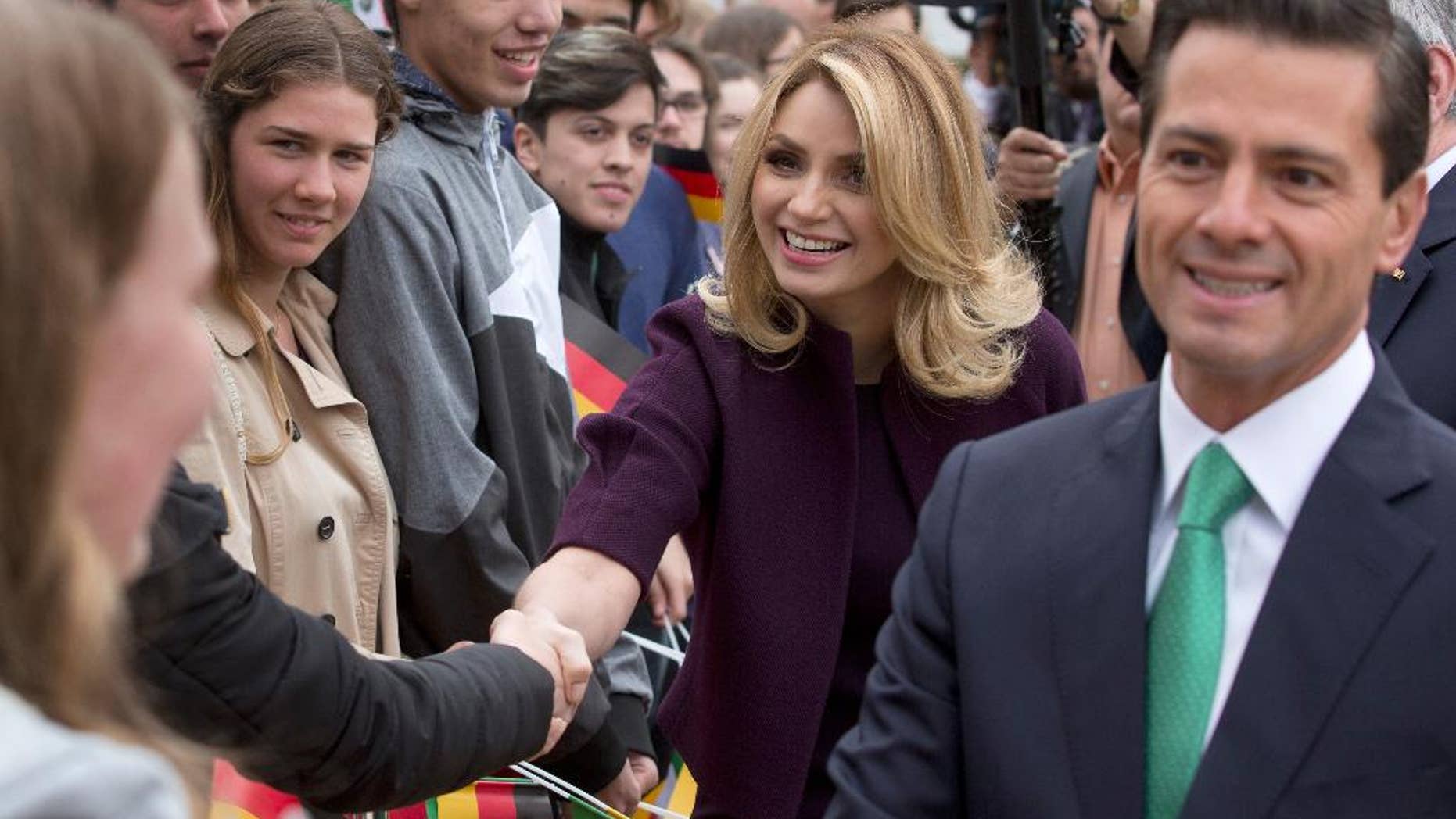 FILE - In this April 11, 2016 file photo, Mexico's President Enrique Pena Nieto, right, and his wife Angelica Rivera de Pena greet students as they arrive to meet with Germany's President Joachim Gauck at Bellevue Palace in Berlin, Germany. Pena Nieto apologized on Monday, July 18, 2016 for a 2014 scandal involving a mansion his wife bought from a firm that won lucrative contracts with his administration. (AP Photo/Michael Sohn, File)