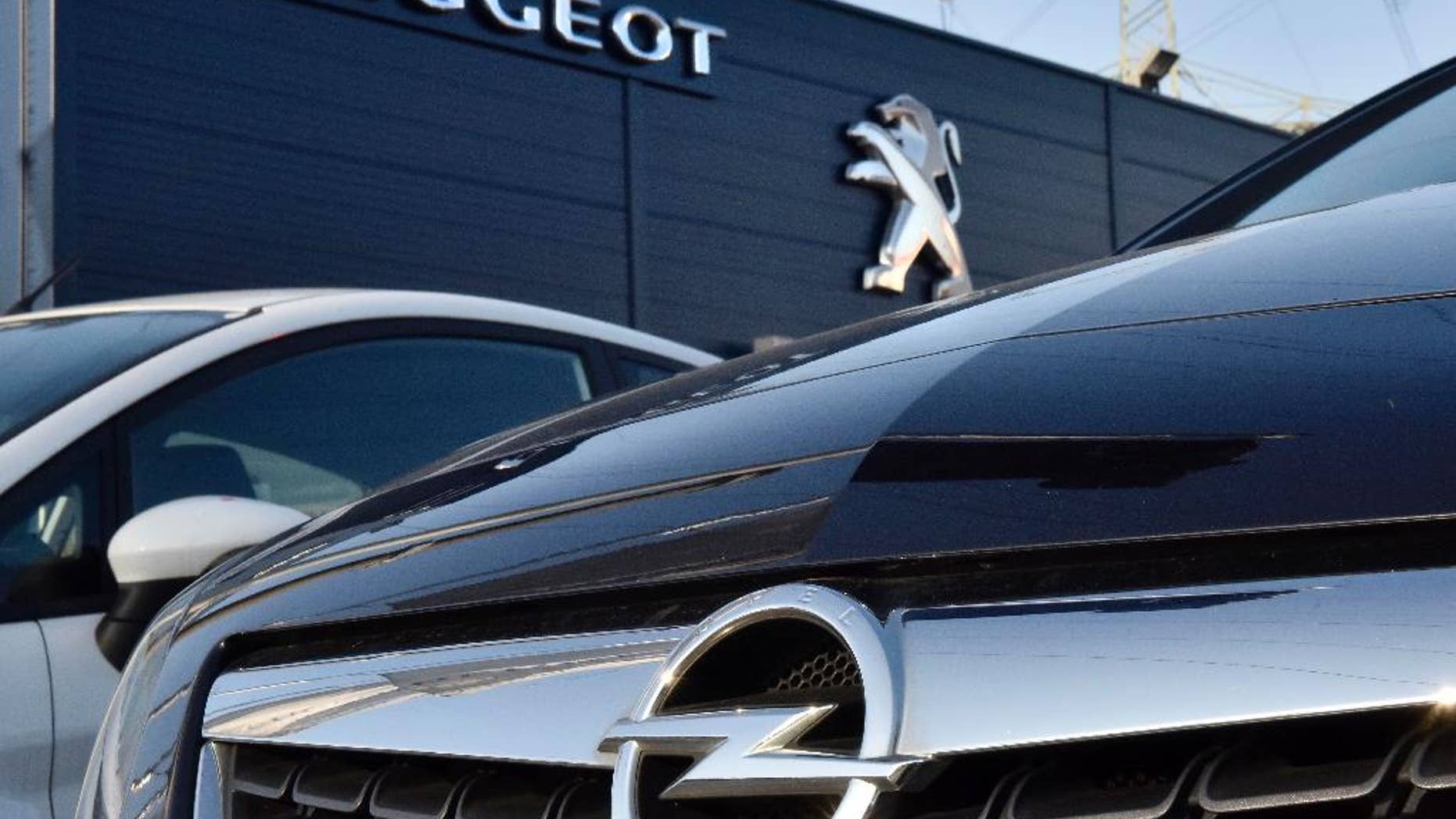 An Opel car, in front, is offered for sale by a Peugeot dealer in Gelsenkirchen, Germany, Tuesday, Feb. 14, 2017. France's PSA Group, maker of Peugeot and Citroen cars, says it's exploring a takeover of Opel, General Motors' money-losing European business. (AP Photo/Martin Meissner)