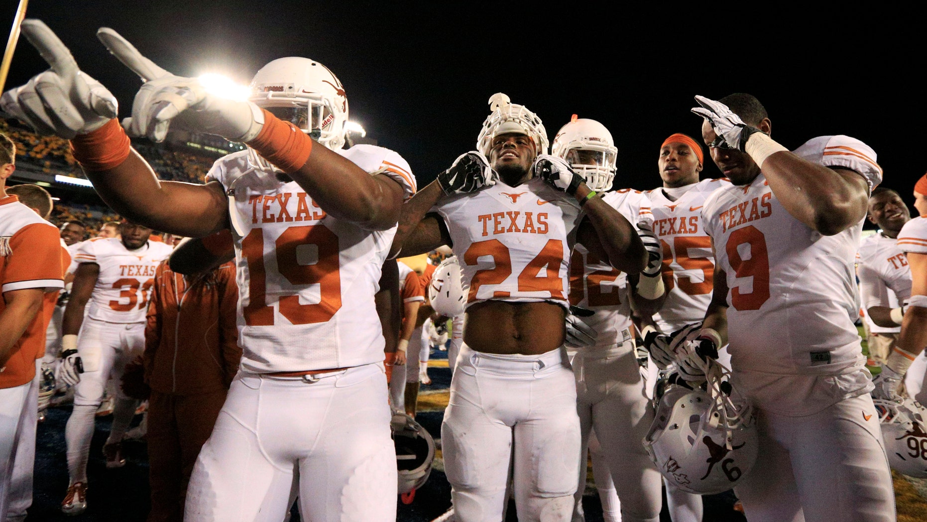 Texas' Peter Jinkens (19), Antwuan Davis (24), Johnathan Gray (32), M.J. McFarland (85) and John Harris (9) celebrate in front of their fan section after the team's 47-40 win in overtime over West Virginia during an NCAA college football game in Morgantown, W.Va., on Saturday, Nov. 9, 2013. (AP Photo/Christopher Jackson)