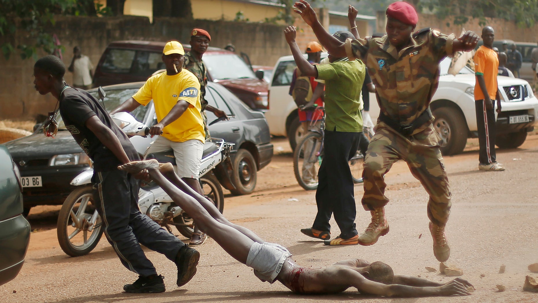 GRAPHIC CONTENT - Newly enlisted FACA (Central African Armed Forces) soldiers drag the lifeless body of a suspected Muslim Seleka militiaman moments after Central African Republic Interim President Catherine Samba-Panza addressed the troops in Bangui, Wednesday Feb. 5, 2014. The victim was lynched by hundreds of recruits, pelting him with bricks and mutilating his body with knives. (AP Photo/Jerome Delay)