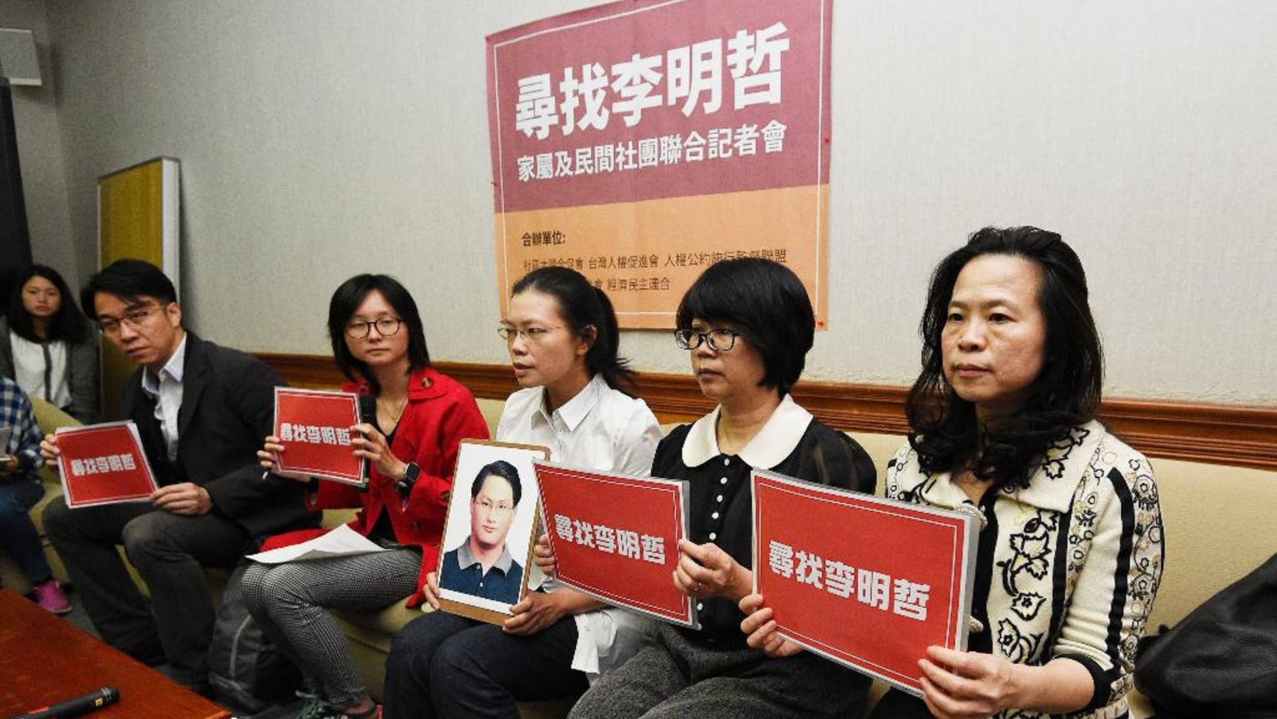In this photo taken Friday, March 24, 2017, Lee Ching-yu, third from right holds up a photo of her missing husband and Taiwanese pro-democracy activist Lee Ming-che during a press conference with other representatives of non-governmental organizations calling for help to find his whereabouts in Taipei, Taiwan. Lee believed to be in Chinese custody may have attracted the attention of China's security services after he used the social media site WeChat to discuss China-Taiwan relations, a colleague said Tuesday. Chinese characters on cards read "Finding Lee Ming-che" (AP Photo)