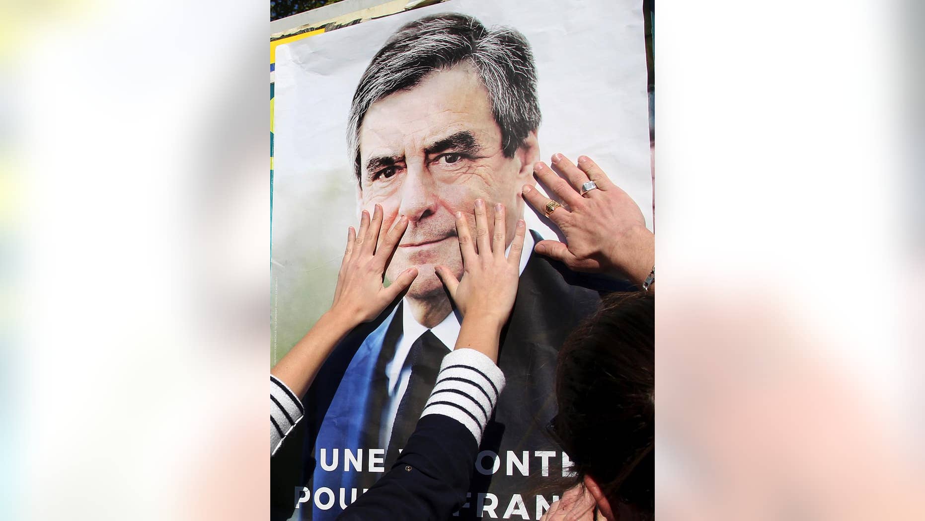 Supporters of conservative presidential candidate Francois Fillon glue a campaign poster in Bayonne, southwestern France, Wednesday, April 19, 2017. The two-round presidential election is set for April 23 and May 7. (AP Photo/Bob Edme)