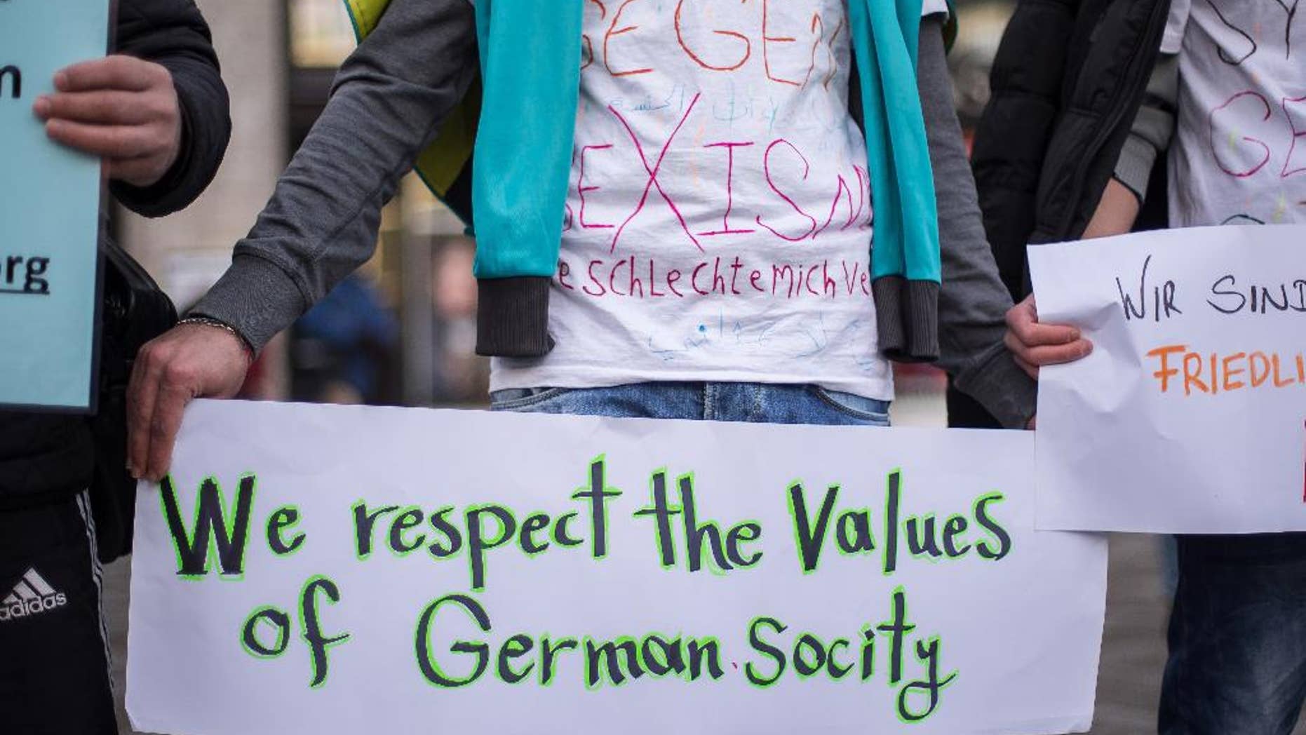 FILE - In this Jan. 16, 2016 file photo a participant at the demonstration 'Syrian refugees say no to the Cologne assaults!' holds a sign in Cologne, Germany. According to police reports, numerous women were sexually harassed and robbed in front of Cologne central station on New Year's Eve. German lawmakers are debating a bill that would make it easier for victims of sex crimes to file criminal complaints, Thursday, July 7, 2016. (Maja Hitij/dpa via AP, file)