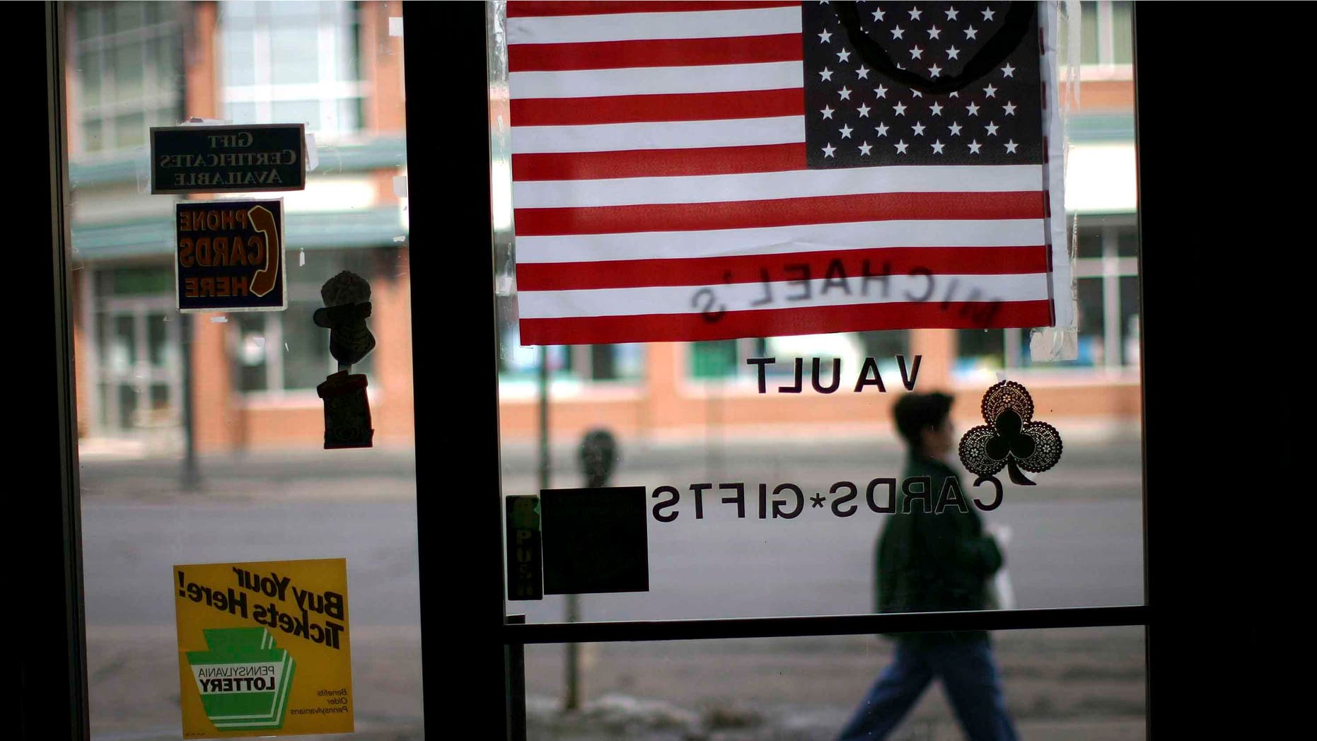 HAZLETON, PA - MARCH 14: A woman walks pass an American flag in a store window March 14, 2007 in Hazleton, Pennsylvania. A new city ordinance in Hazleton has caused members of the large Latino community to fear discrimination and have concern for their future in the town. The city of Hazleton and its aggressive policy on illegal immigration is the subject of a federal trial that is being viewed nationally as a landmark case on immigration. In a move that caused outrage among Latino residents this past summer, city officials in Hazleton adopted ordinances that target illegal immigrants in housing, language use and employment. The ordinance, called the Illegal immigration Relief Act, has been put on hold while the case is challenged in federal court in Scranton by the American Civil Liberties Union and the Puerto Rican Legal Defense and Education Fund. At least 80 towns and cities across the nation have adopted similar measures against illegal immigrants. (Photo by Spencer Platt/Getty Images)