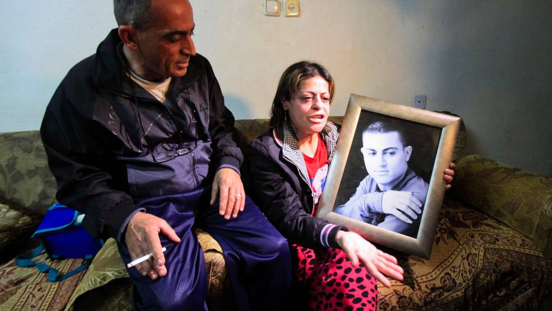 March 10, 2015: Hind, the mother of Muhammad Said Ismail Musallam, holds a picture of her son as she speaks to the Associated Press while seated next to her husband Said Musallam at their home.
