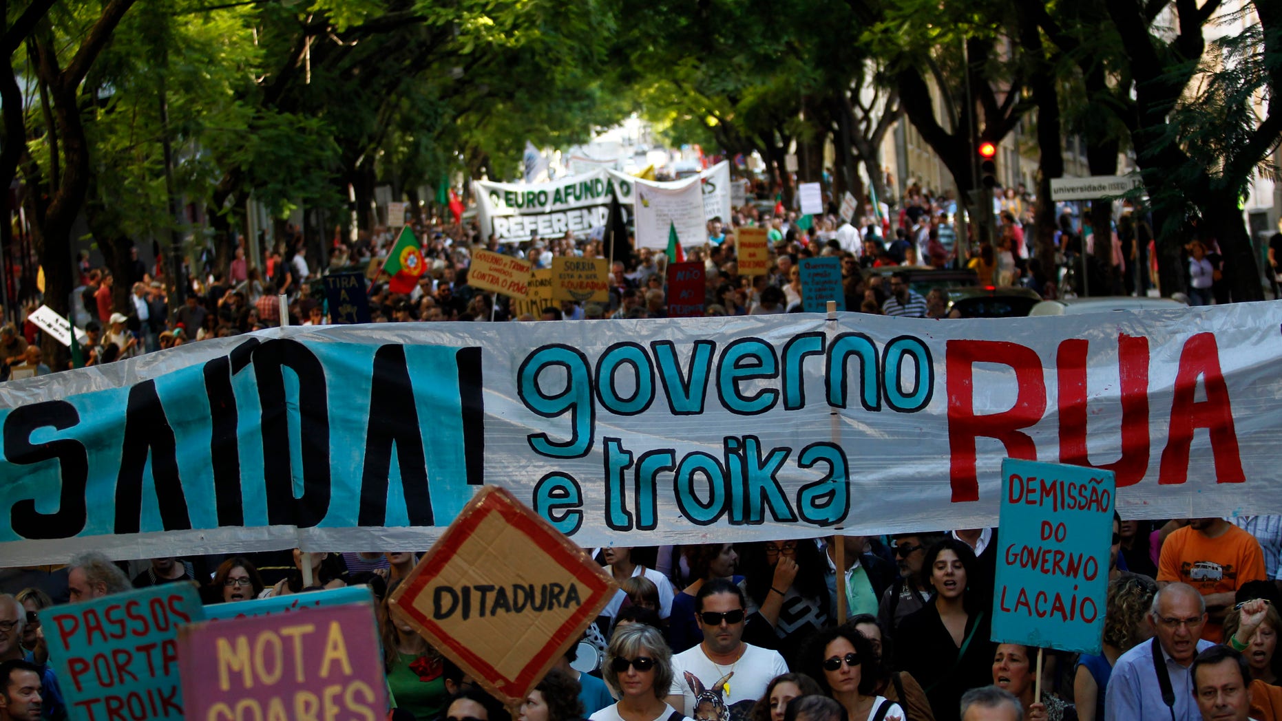 People, some of them holding a large banner that reads in Portuguese: "There is a Way! Government and Troika Out!", march towards the Portuguese parliament during a demonstration against austerity measures taken by the Portuguese government in exchange for an euro 78 billion (US$ 107.6 billion) bailout needed in 2011, in Lisbon, Saturday, Oct. 26, 2013. Others placards read in Portuguese: "Dictatorship" and "Resignation of the lackey government". (AP Photo/Francisco Seco)