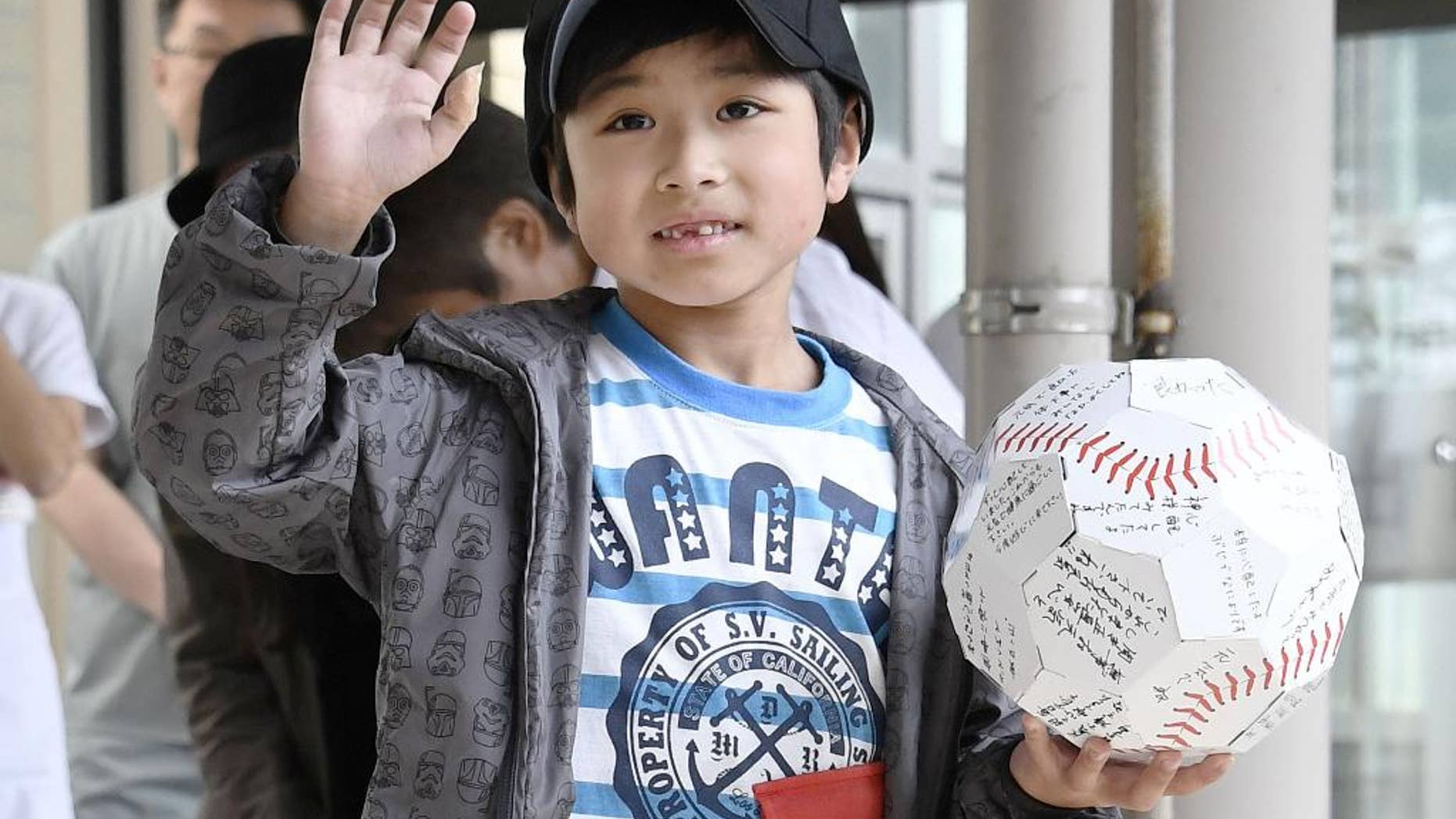 FILE - In this June 7, 2016 file photo, Yamato Tanooka, who survived almost a week in a forest after his parents left him at the side of a road, waves as he leaves a hospital in Hakodate on the northern island of Hokkaido. The Japanese boy was released from a hospital this week, smiling and waving at a crowd cheering the happy ending. Public criticism of the father, who made 7-year-old Tanooka get out of the car to punish him for misbehavior, has faded, and police reportedly won’t pursue charges. (Daisuke Suzuki/Kyodo News via AP, File) JAPAN OUT, MANDATORY CREDIT