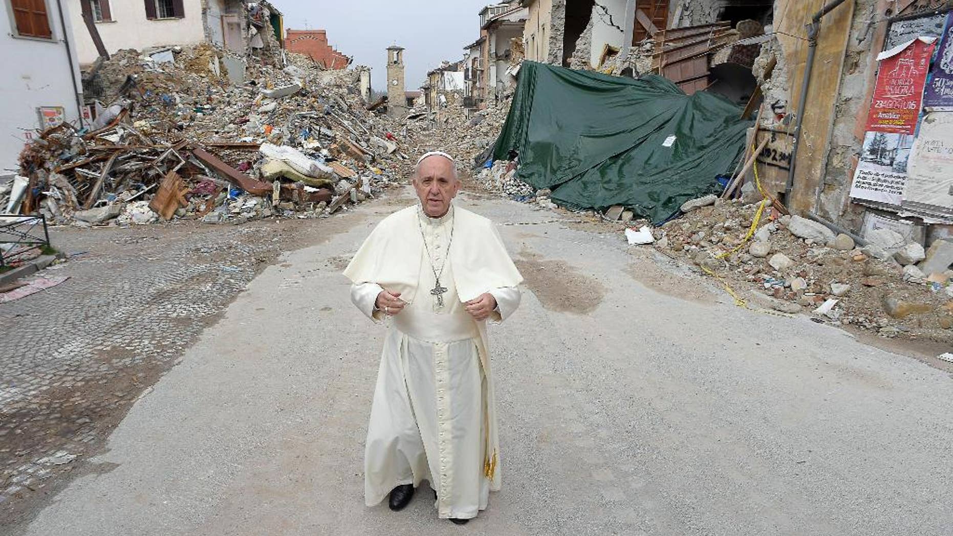 Pope Francis stands in front of rubble, with the standing bell tower in the background, of the quake-struck town of Amatrice.