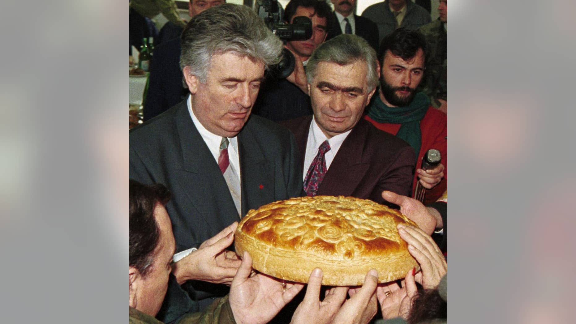 FILE - In this Jan. 9, 1996 file photo, Bonsnian Serb wartime leader Radovan Karadzic, left, and Serb member of Bosnian Presidency Momcilo Krajisnik roll the cake, marking St. Stevan, Republic of Srpska patron-saint day. Serbia's president Tomislav Nikolic has met a convicted Bosnian Serb war criminal Momcilo Krajisnik urging the protection of human rights for the Serbs living in the Balkan regions. (AP Photo/Darko Vojinovic, File)