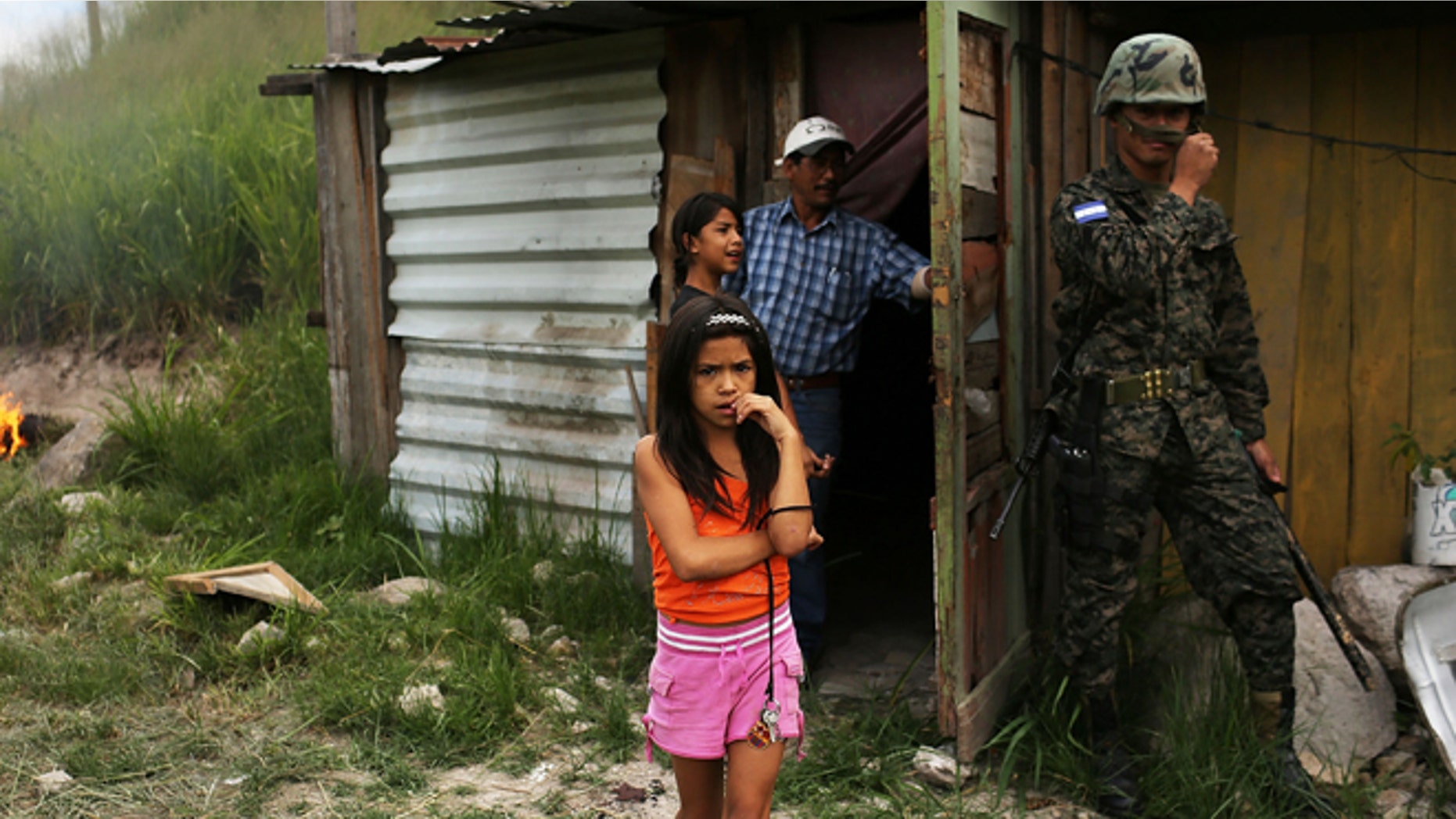 TEGUCIGALPA, HONDURAS - JULY 20: A young girl and her family stand by their home as police and the army force them and their neighbors to dismantle the shanty town after the government claimed that the settlement was illegal on July 20, 2012 in Tegucigalpa, Honduras. Land disputes are becoming increasingly frequent in Honduras which is alarming the nation's business class while sowing fears of increased political violence. In a nation where 72% of the poorest landowners hold only 11.6% of cultivated land, tensions are rising as the poor have few places to go and little opportunities for productive employment. Honduras now has the highest per capita murder rate in the world and its capital city, Tegucigalpa, is plagued by violence, poverty, homelessness and sexual assaults. With an estimated 80% of the cocaine entering the United States now being trans-shipped through Honduras, the violence on the streets is a spillover from the ramped rise in narco-trafficking. (Photo by Spencer Platt/Getty Images)