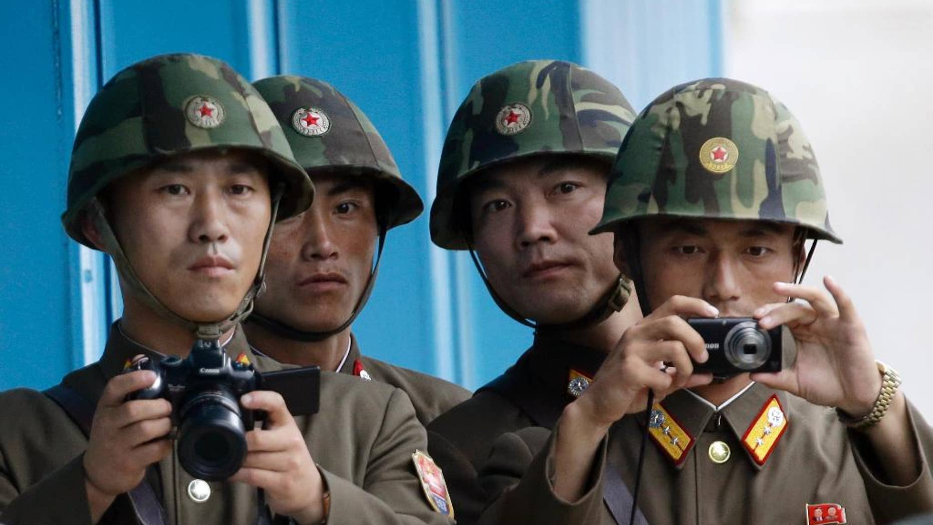 In this Saturday, July 27, 2013 photo, North Korean soldiers watch the south side with cameras at the border village of Panmunjom, which has separated the two Koreas since the Korean War, in Paju, north of Seoul, South Korea. Seoul defense officials said South Korean troops have fired warning shots after North Korean soldiers approached too close to the border separating the rival countries. (AP Photo/Lee Jin-man)