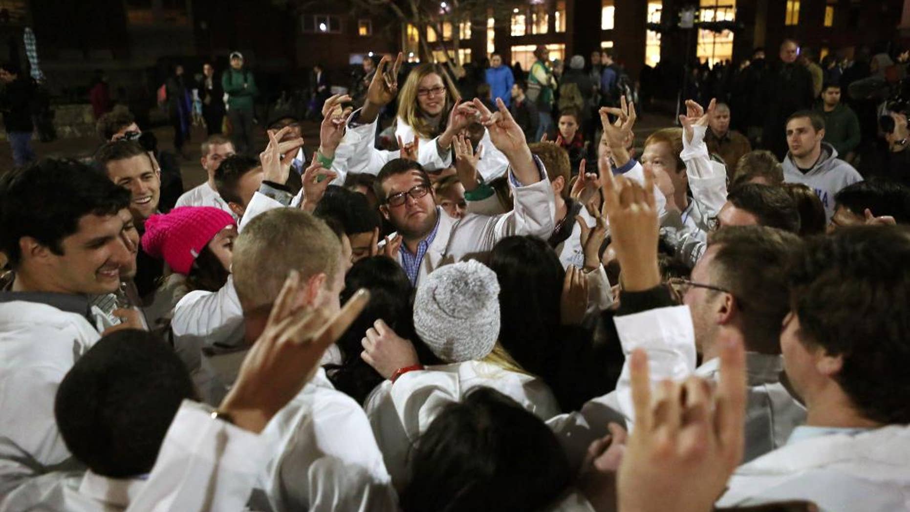 UNC Dental School students make the North Carolina State University Wolfpack sign following a candlelight vigil for their slain classmate, who, along with two others, was killed at a condominium near UNC-Chapel Hill, Wednesday, Feb. 11, 2015, in Chapel Hill, N.C. Craig Stephen Hicks appeared in court on charges of first-degree murder in the Tuesday deaths of Deah Shaddy Barakat, his wife Yusor Mohammad and her sister Razan Mohammad Abu-Salha. (AP Photo/The News & Observer, Al Drago)