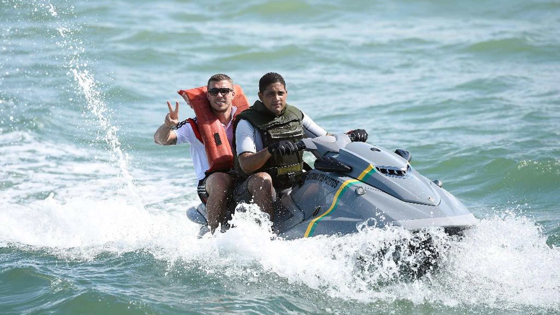 German national soccer player Lukas Podolski poses on a jet ski in Santo Andre near Porto Seguro, Brazil, Tuesday, June 10, 2014. The German team got some motivation help from explorer and adventurer Mike Horn during a sailing outing near their camp on Brazil's Atlantic coast. (AP Photo/Markus Gilliar, pool)