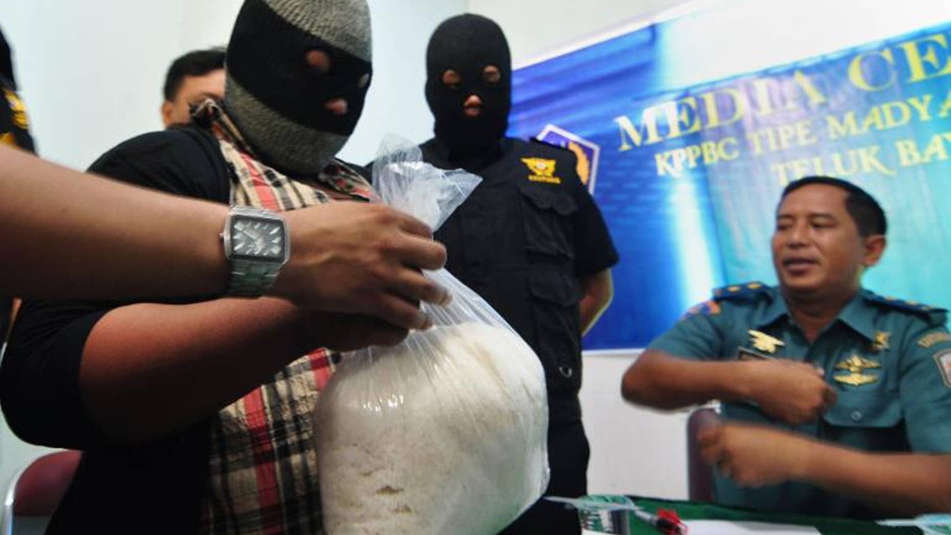 File picture shows an unidentified suspected drugs courier (L) holding a bag containing "crystal meth" (methamphetamine hydrochloride) at the customs office in Padang, West Sumatra province on May 28, 2013.