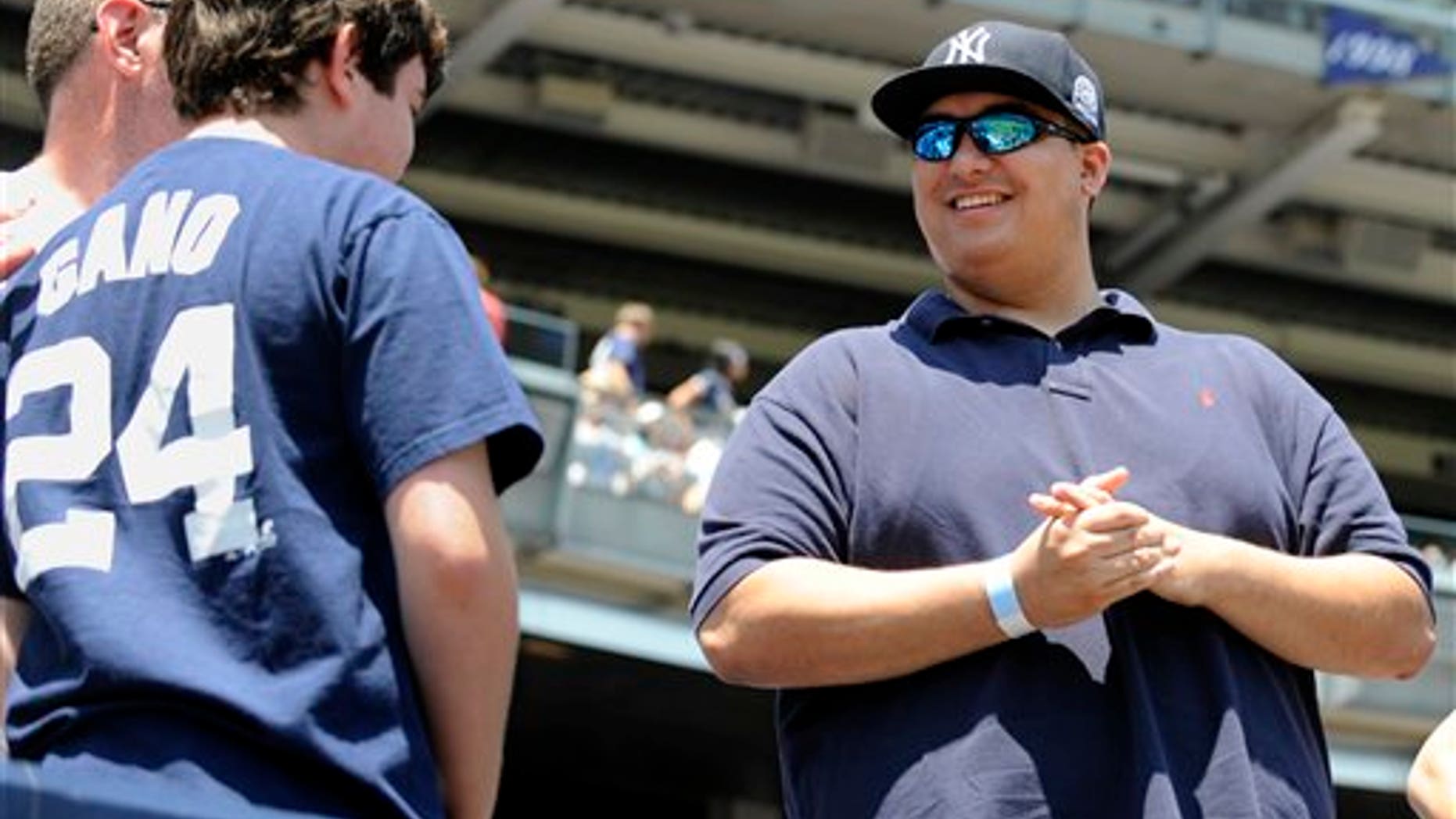 Fans talk with Christian Lopez, right, before the New York Yankees' baseball game against the Tampa Bay Rays on Sunday, July 10, 2011, at Yankee Stadium in New York. Lopez caught a home run Saturday by Derek Jeter which was Jeter's 3,000th career hit, and returned the ball to Jeter. (AP Photo/Bill Kostroun)