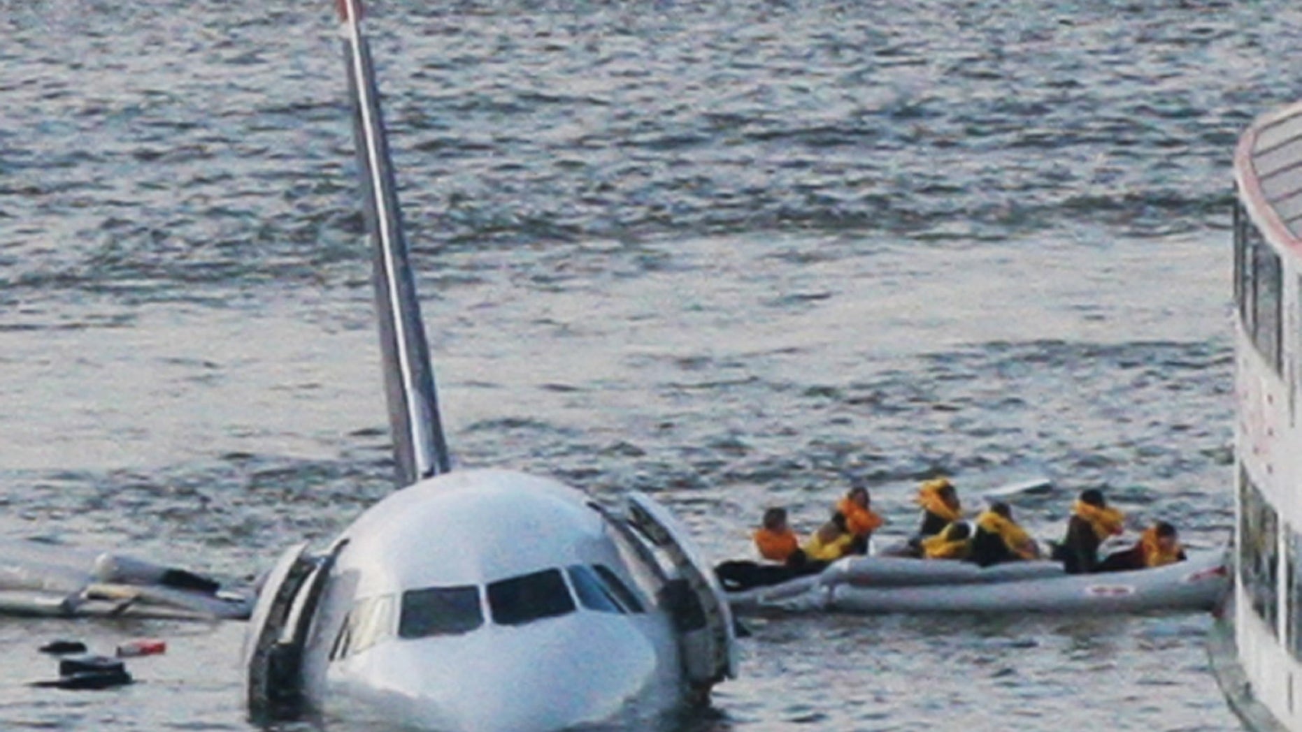 FILE - In this Jan. 15, 2009 file photo, passengers in an inflatable raft move away from US Airways Flight 1549 that went down in the Hudson River in New York. Capt. Chesley "Sully" Sullenberger III, First Officer Jeff Skiles and some passengers who were on the plane on Wednesday, Jan. 15, 2014 are expected to join some of the ferry crews who rescued them from the cold waters five years ago. (AP Photo/Bebeto Matthews, File)
