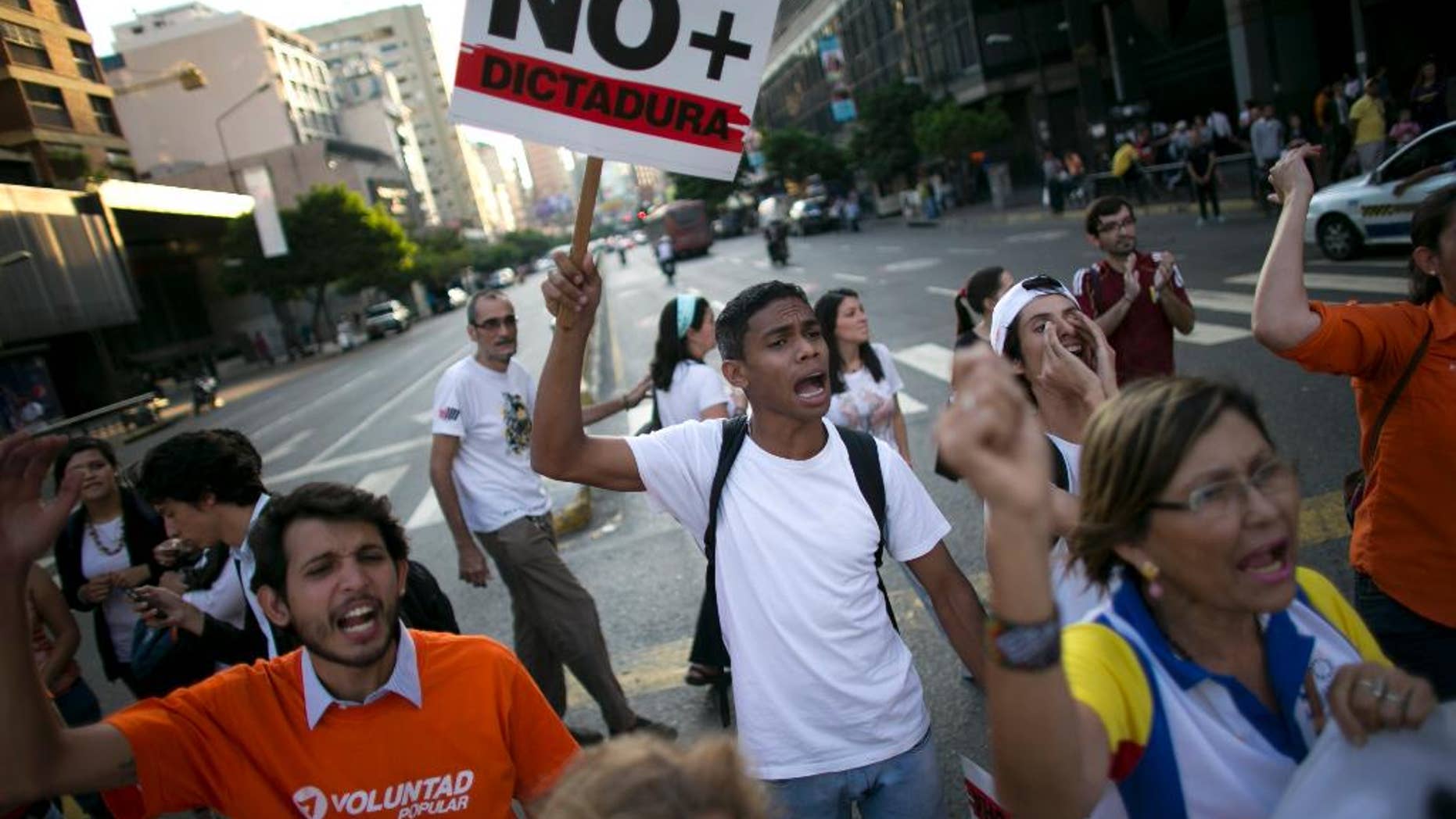 A man holds up a sign that reads in Spanish: "No more dictatorship," during a protest in Caracas, Venezuela, Friday, March 31, 2017. Venezuelans have been thrust into a new round of political turbulence after the government-stacked Supreme Court gutted congress of its last vestiges of power, drawing widespread condemnation from foreign governments and sparking protests in the capital. (AP Photo/Ariana Cubillos)