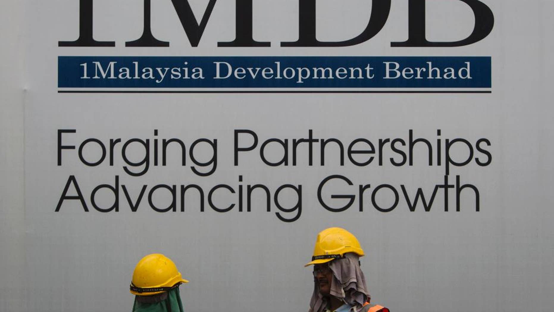 FILE - In this May 14, 2015 file photo, construction workers chat in front of a billboard for state investment fund 1 Malaysia Development Berhad (1MDB) at the fund's flagship Tun Razak Exchange development in Kuala Lumpur, Malaysia. Singapore regulators ordered the closure Tuesday, Oct. 11, 2016 of Falcon Private Bank, citing alleged slack controls for transfers and improper conduct related to 1MDB, an indebted Malaysian state fund. (AP Photo/Joshua Paul, File)