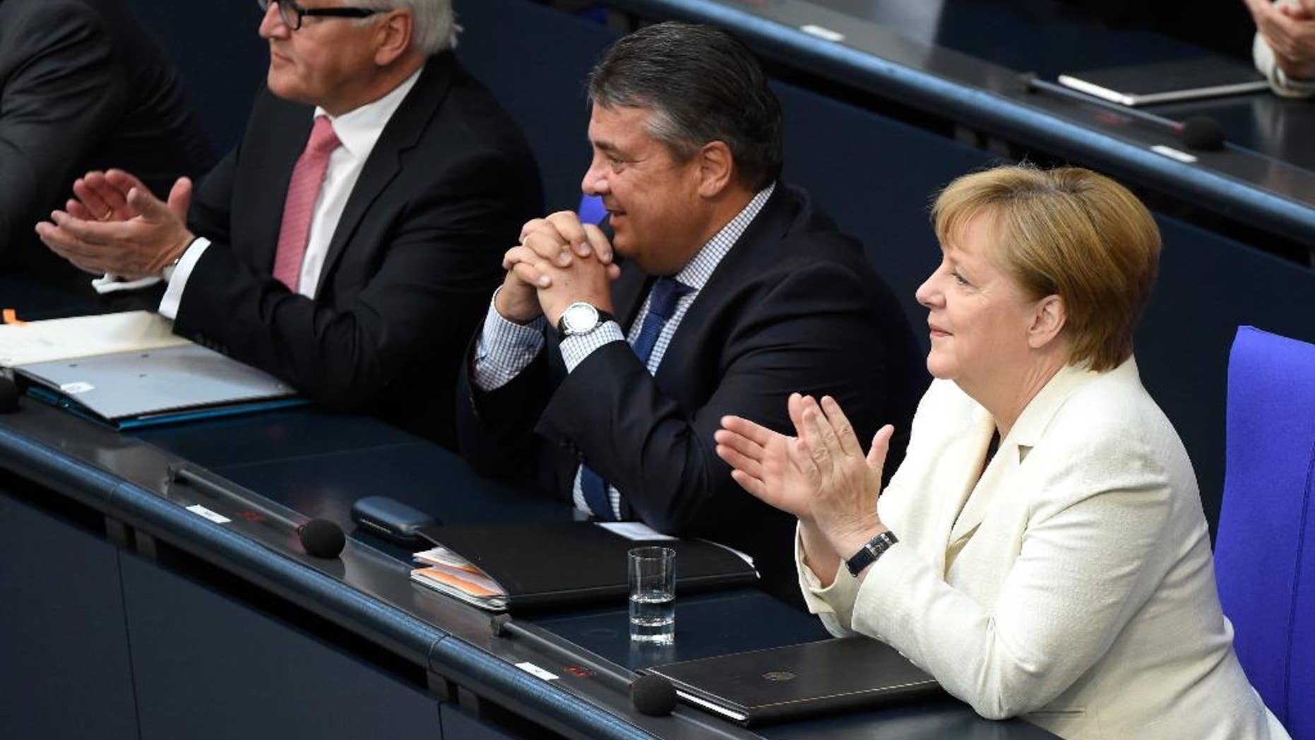 German chancellor Angela Merkel sits next to minister of the economy, Sigmar Gabriel and Foreign Minister Frank-Walter Steinmeier, from right, in the German parliament Bundestag in Berlin, Germany, Thursday, July 7 2016. In her government declaration the chancellor commented on the German strategy for the upcoming NATO summit. (Wolfgang Kumm/dpa via AP)