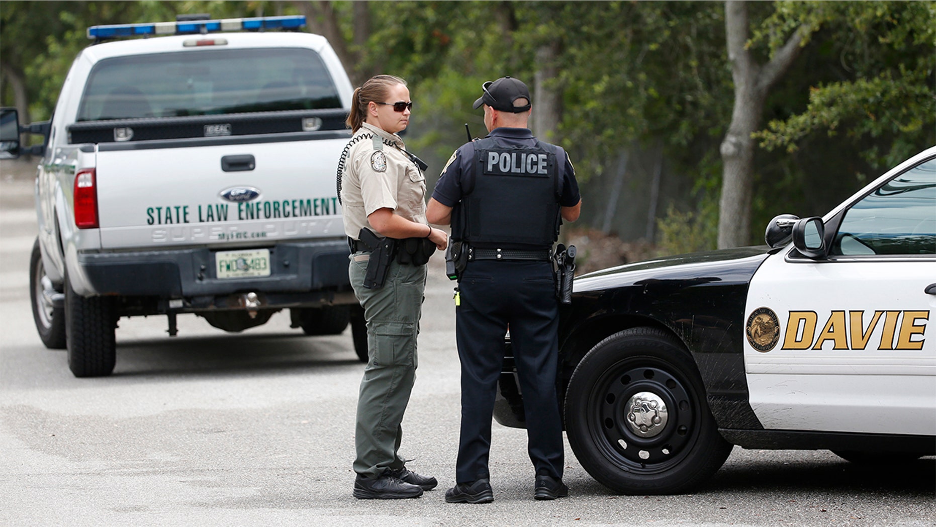 Law enforcement officers gather at the entrance of Silver Lakes Rotary Nature Park on Friday in Davie, Florida.