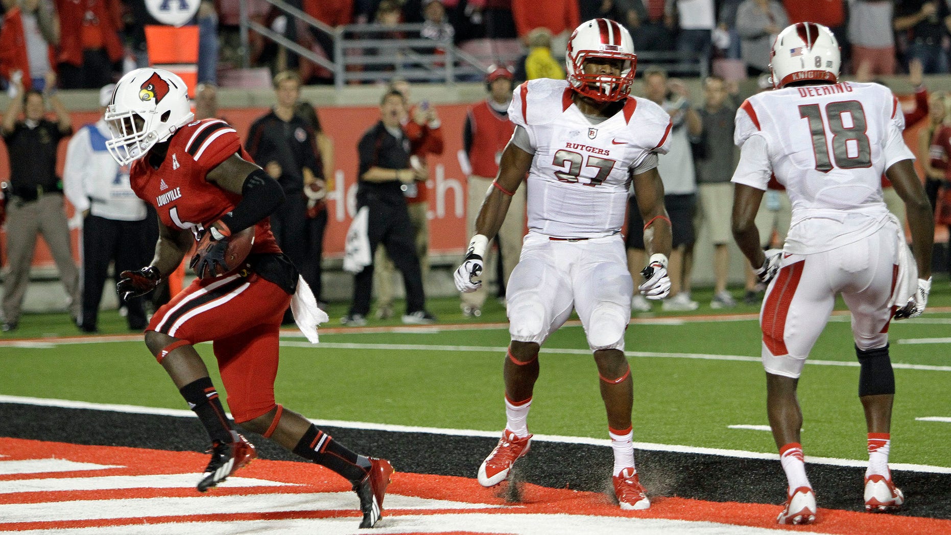 Louisville's Eli Rogers, left, splits Rutgers defenders Jamal Merrell (27) and Jeremy Deering (18) to score on a touchdown reception late in the fourth quarter in their NCAA college football game in Louisville, Ky., Thursday, Oct. 10, 2013. Louisville beat Rutgers 24-10. (AP Photo/Garry Jones)