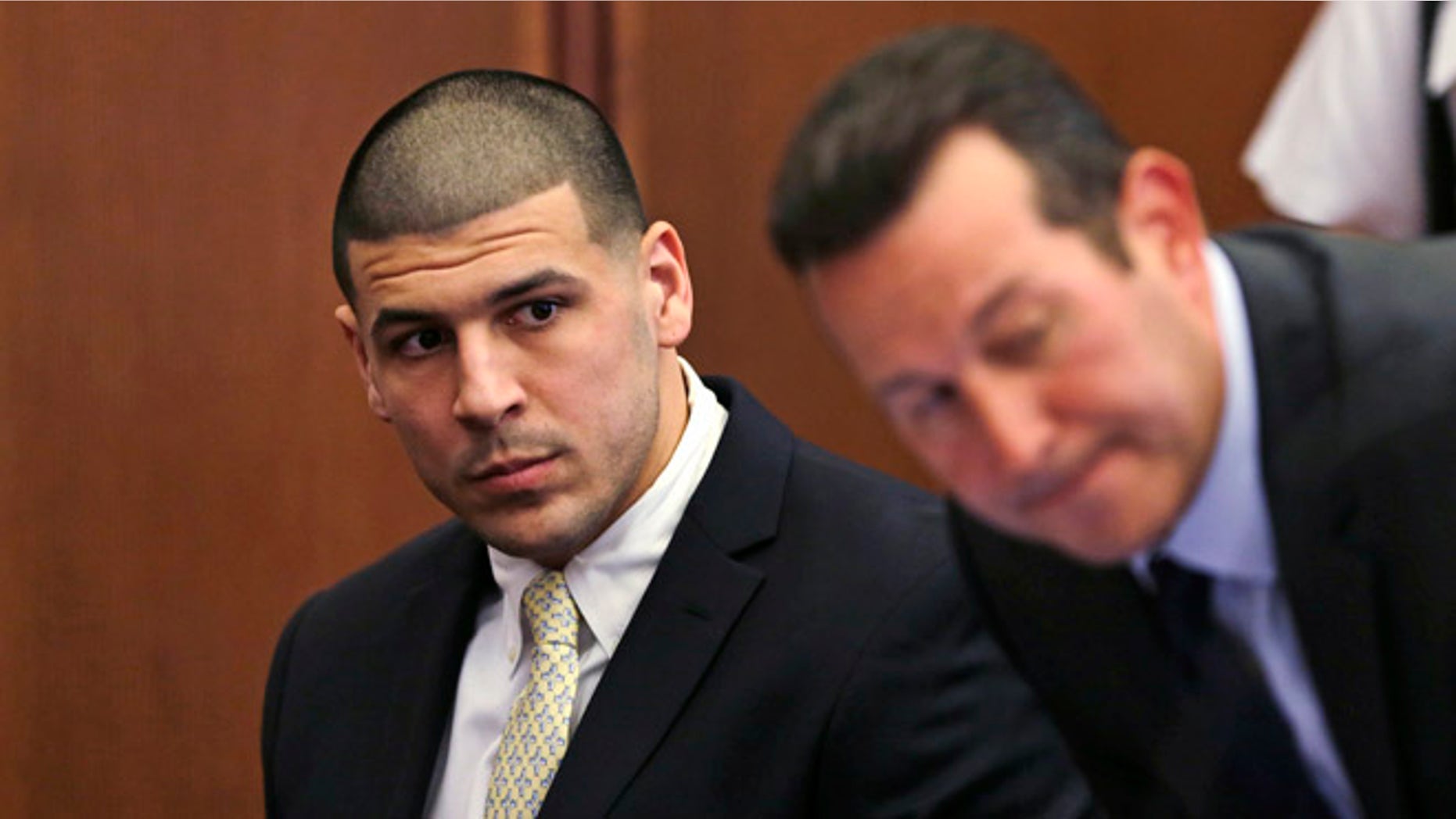 FILE - In this Thursday, July 21, 2016 file photo, Former New England Patriots wide receiver Aaron Hernandez, left, looks down the table at his legal team as his new defense attorney Jose Baez, right, takes a seat during a court appearance at Plymouth Superior Court in Plymouth, Mass. Hernandez is due in Suffolk Superior Court on Tuesday, Aug. 16, for a hearing in the 2012 killings of two men outside a Boston nightclub. Hernandez has pleaded not guilty. (AP Photo/Charles Krupa, Pool, File)