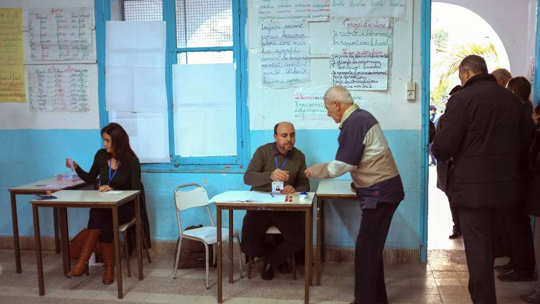 Tunisians check voters' ID prior to cast their ballots in a polling station in Tunis, Tunisia, Sunday, Dec. 21, 2014. Tunisians voted on Sunday for a new president in a runoff between a symbol of the country's previous regimes and a veteran human rights activist that came to power after the revolution of 2011.(AP Photo/Ilyess Osmane)